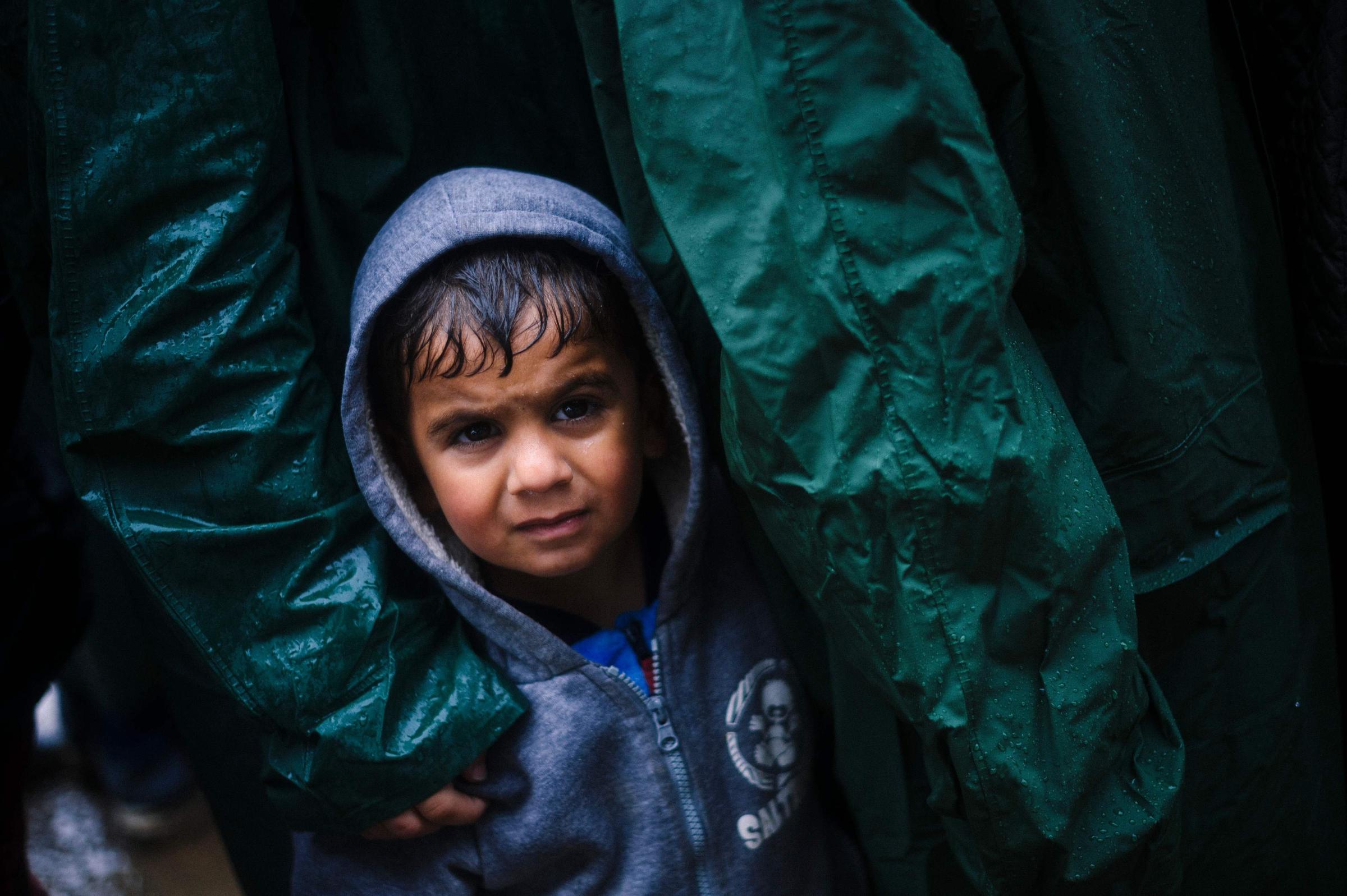 A boy waits in the rain for soup in a makeshift camp for migrants and refugees near the Greek village of Idomeni, on the Greek-Macedonian border, March 9, 2016.