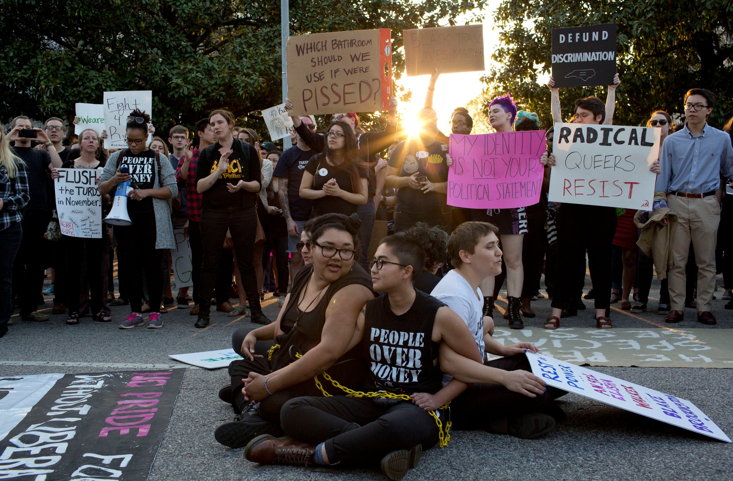 Front from left, demonstrators Jess Jude, Loan Tran and Noah Rubin-Blose, sit chained together in the middle of the street during a protest against House Bill 2 outside of the Governor's Mansion in Raleigh, N.C., on March 24, 2016,.