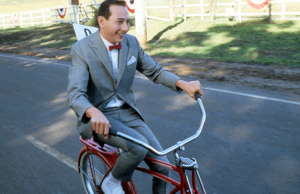 Paul Reubens rides a bike in a scene from the film 'Pee-Wee's Big Adventure', 1985. (Warner Bros. / Getty Images)