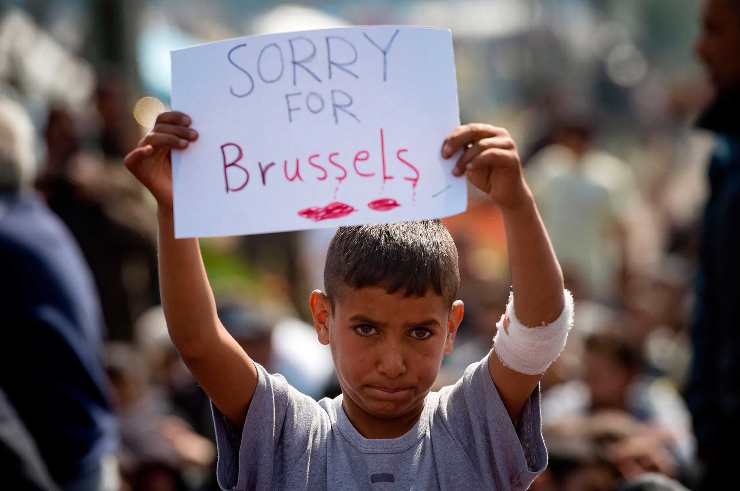 A boy holds a placard expressing sympathy for the victims of the terror attacks in Brussels during a protest at a makeshift camp at the Greek-Macedonian border, near the village of Idomeni, March 22, 2016.