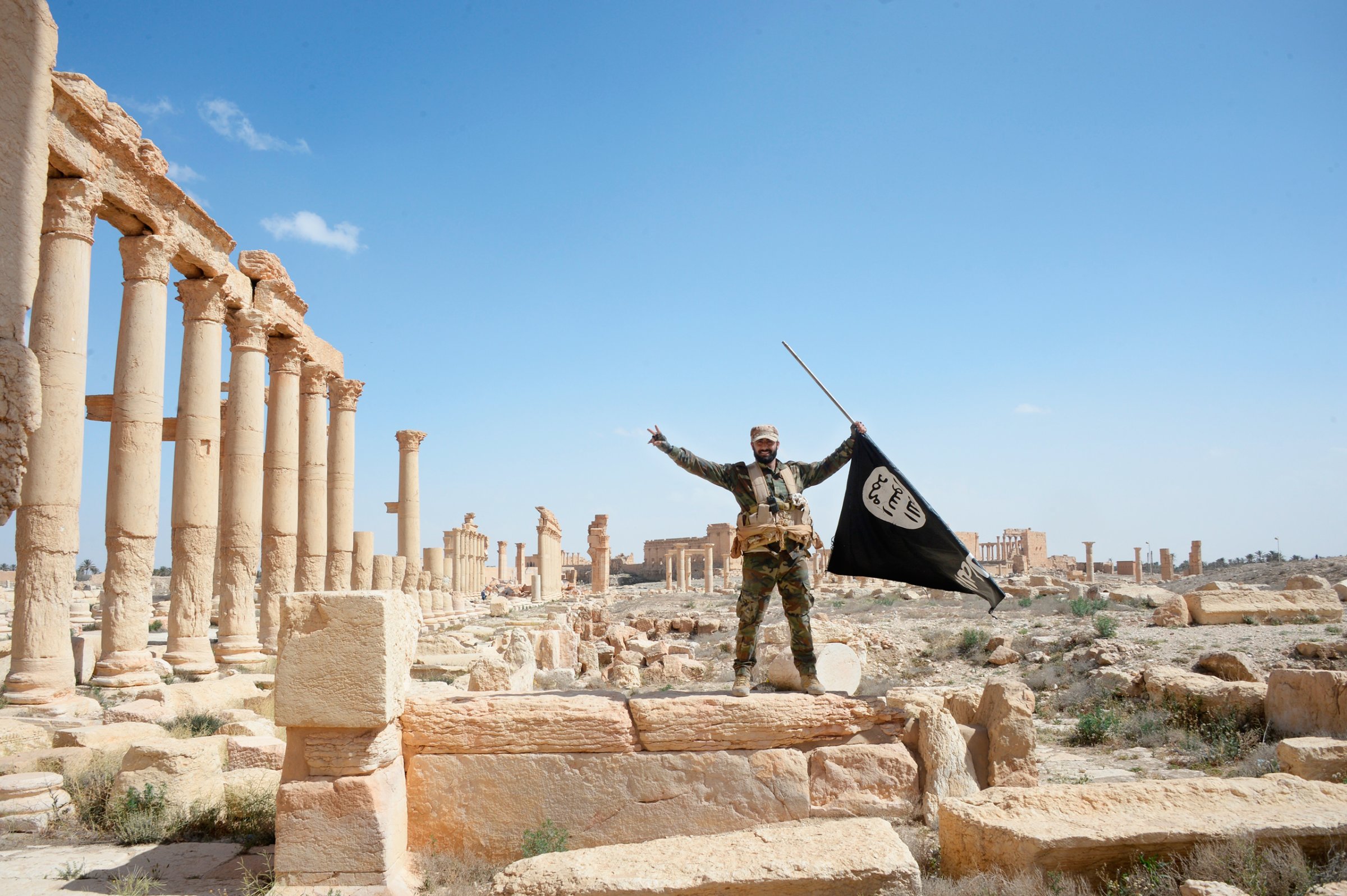 A Syrian army soldier holds an ISIS flag after government troops retake the city of Palmyra