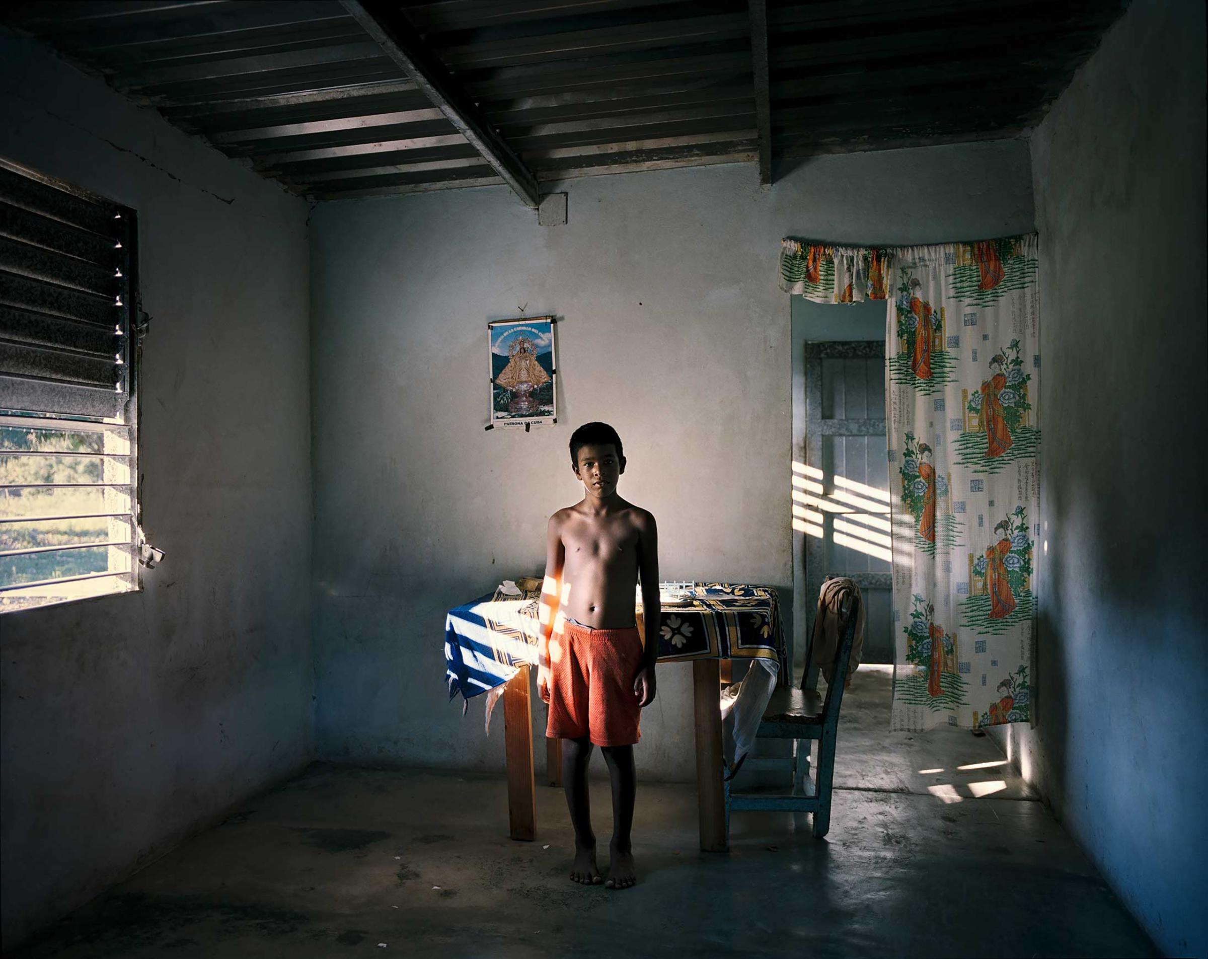 An 8 year old boy in his house on the south coast of Cuba.