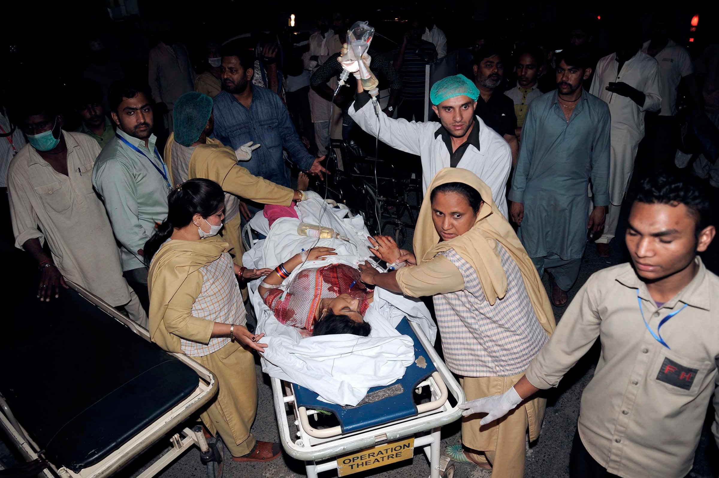 Relatives and emergency workers carry an injured woman to the hospital after at least 70 people were killed in an Easter Sunday bombing at a park in Lahore, Pakistan, March 27, 2016.
