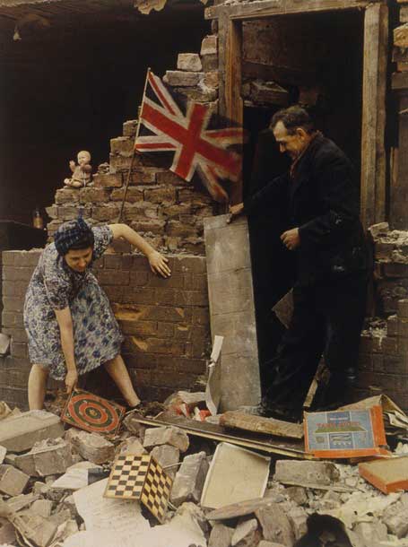 Woman saving board games from bomb wreckage in London. 1939-1945.