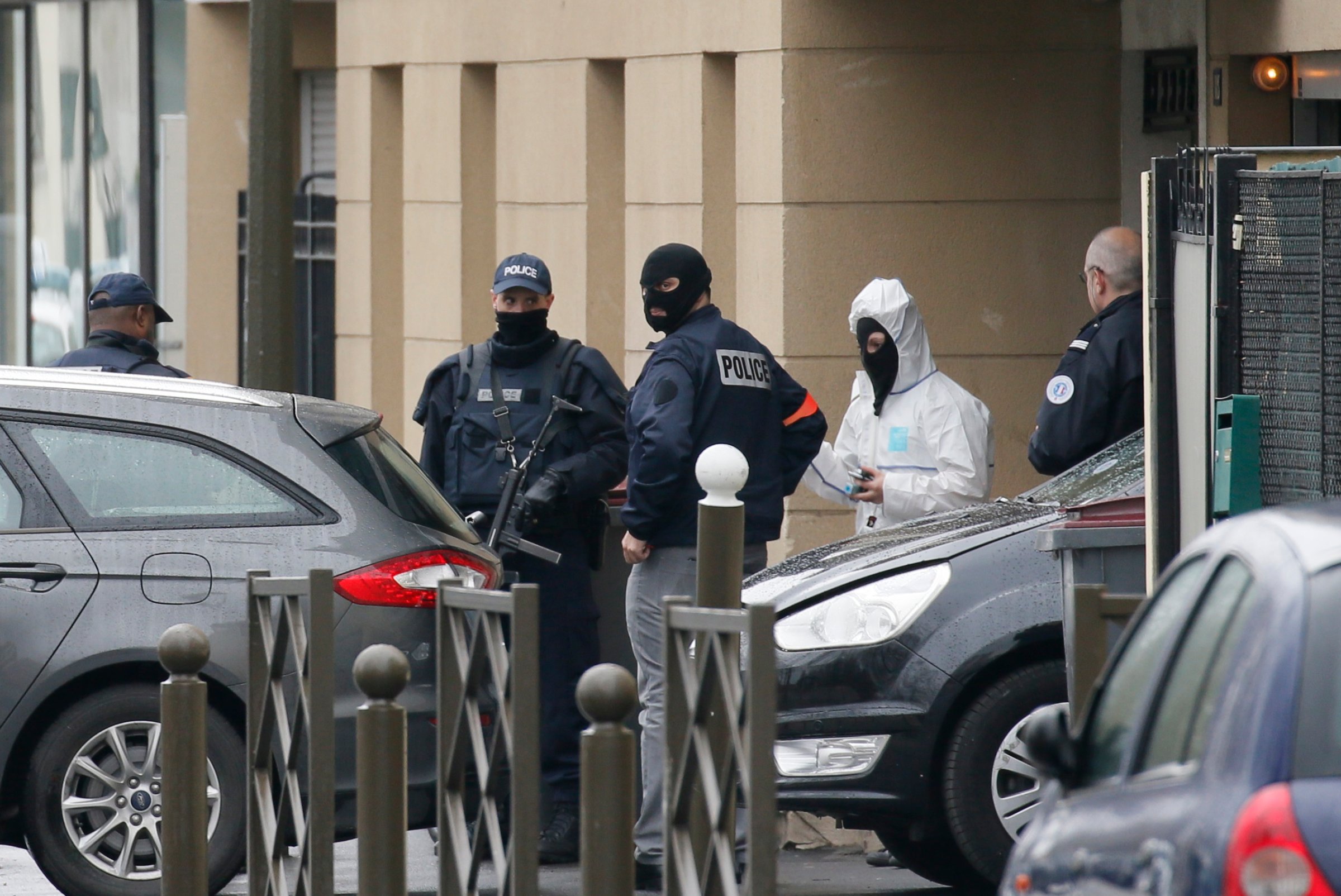 French Police and a forensic expert stand at the entrance of an apartment building after a raid in Argenteuil, a suburb in northern Paris