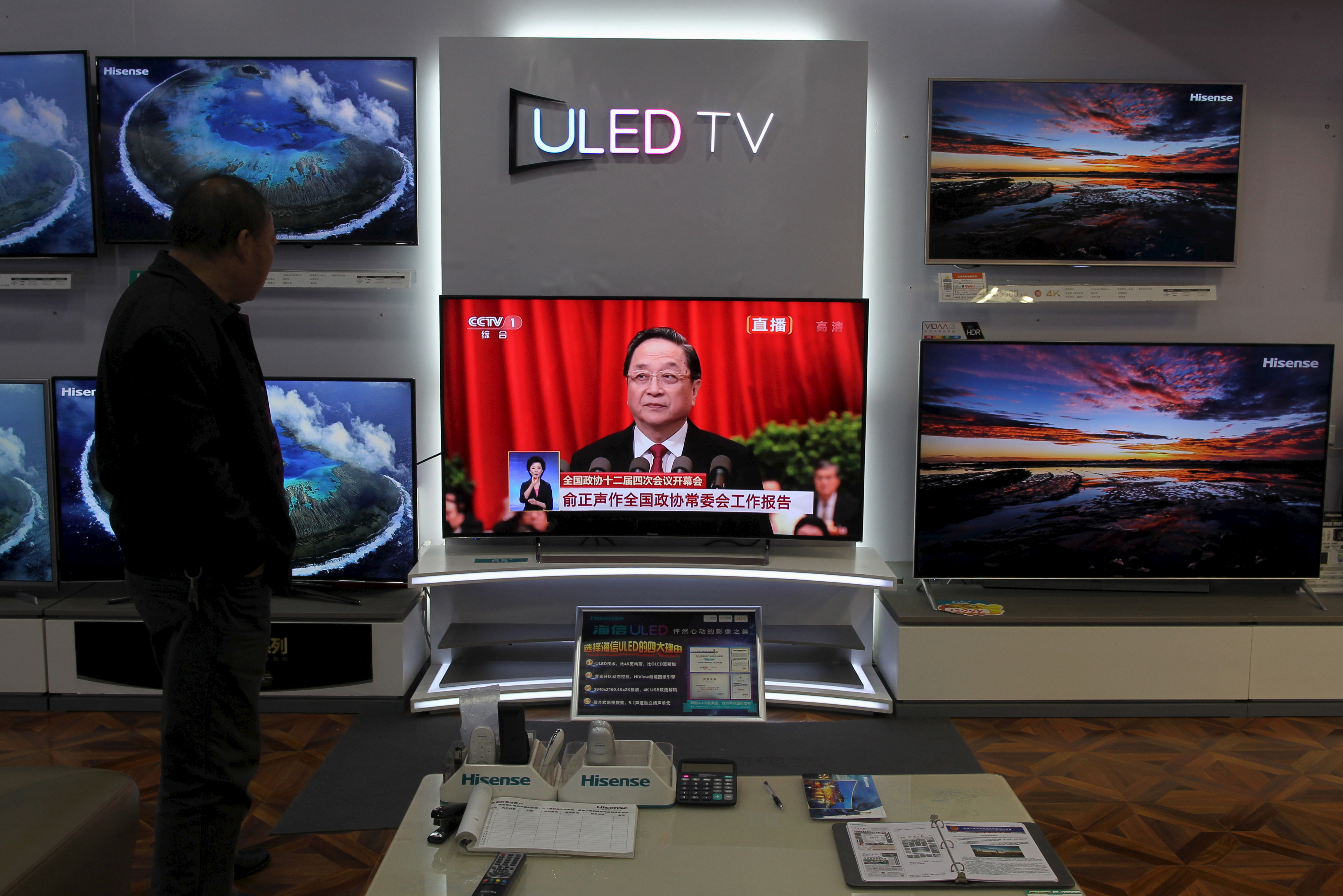 A man watches a TV screen showing live broadcast of Yu Zhengsheng, chairman of the National Committee of the Chinese People's Political Consultative Conference (CPPCC), giving a speech during the opening session of the CPPCC, at a shopping mall in Kunming, the Chinese province of Yunnan, on March 3, 2016 (Wong Campion—Reuters)