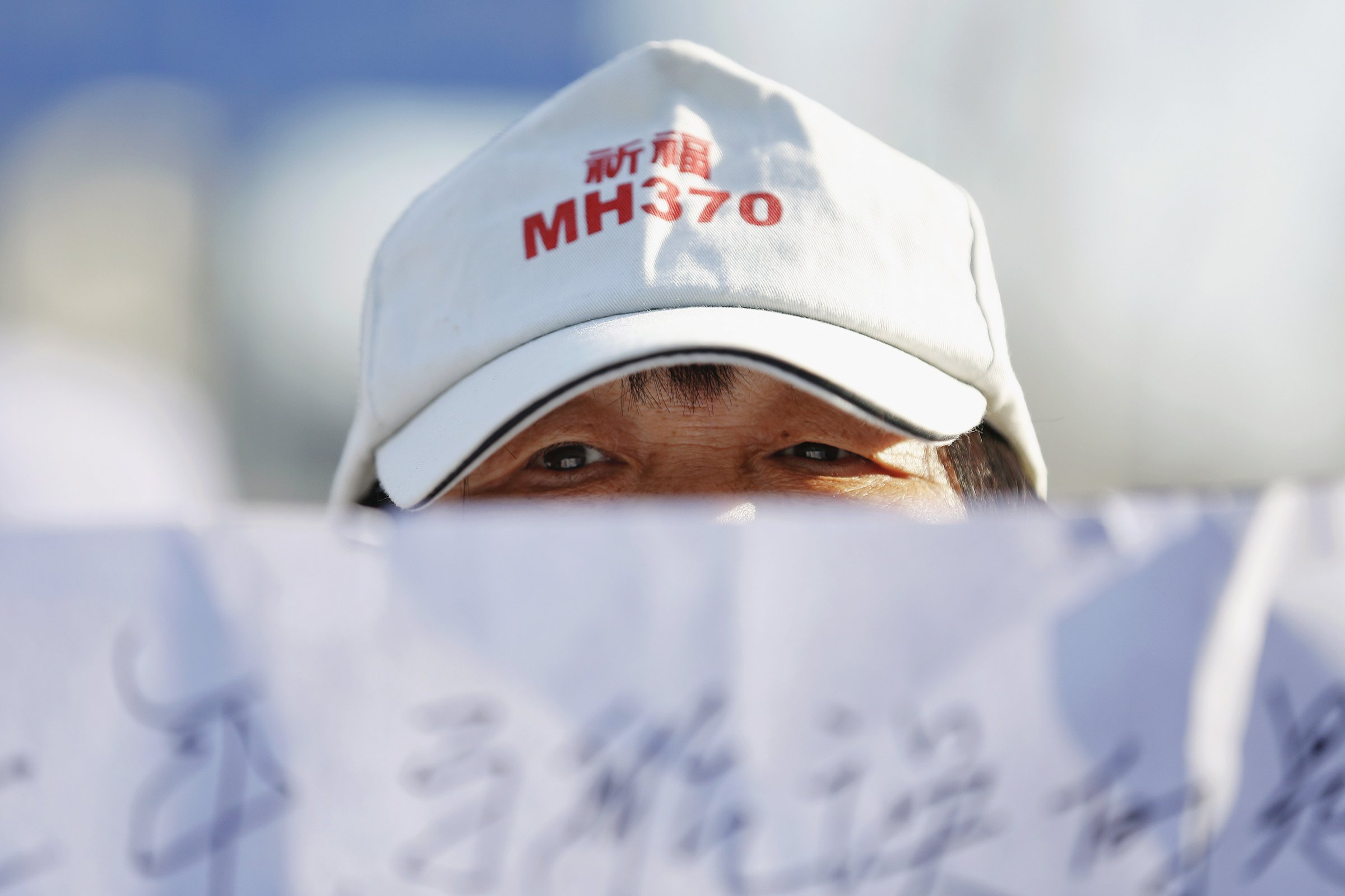 A family member of a passenger onboard Malaysia Airlines flight MH370 which went missing in 2014 holds a banner during a gathering in front of the Malaysian Embassy on the second anniversary of the disappearance of MH370, in Beijing
