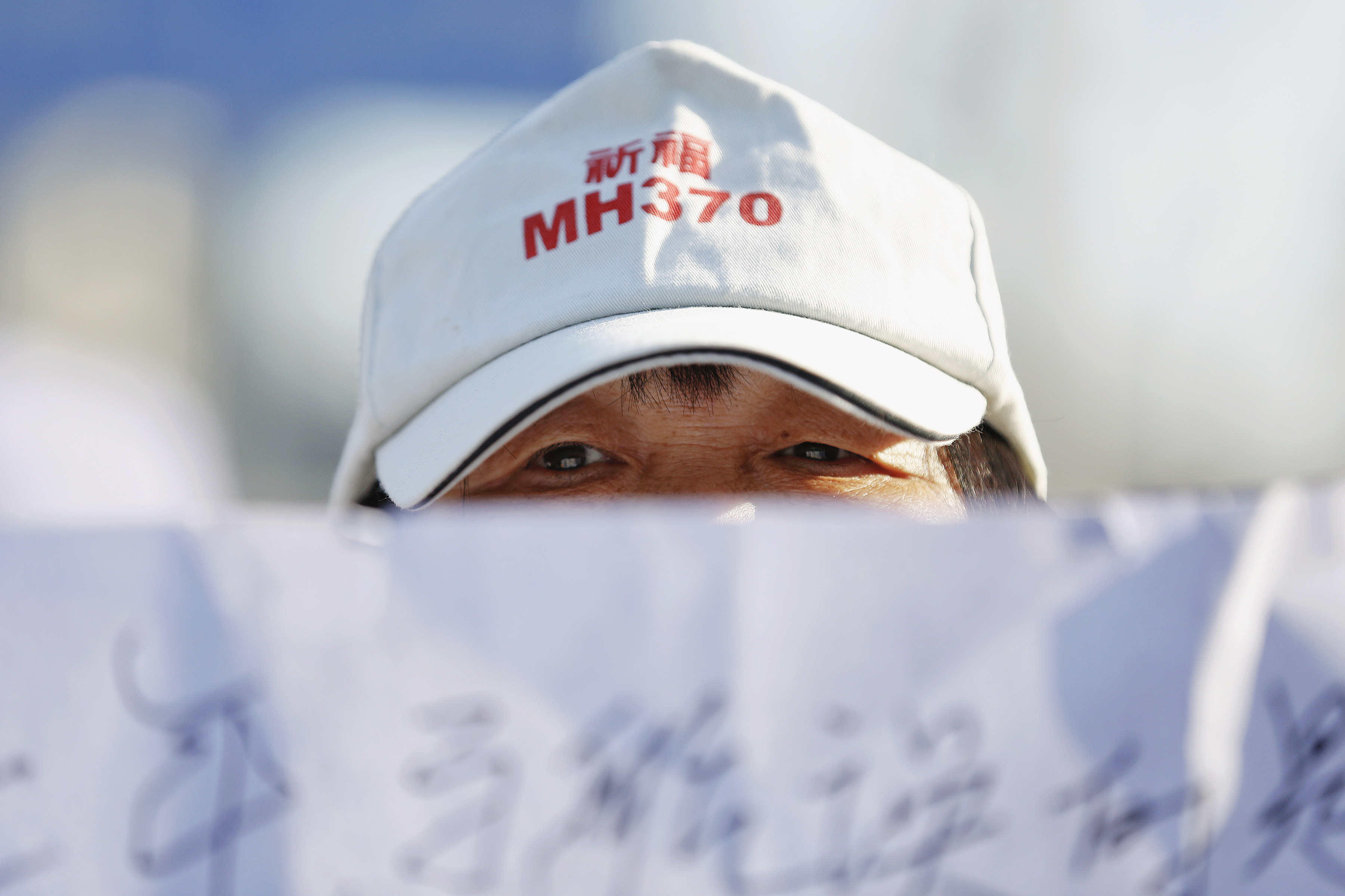 A family member of a passenger onboard Malaysia Airlines flight MH370 which went missing in 2014 holds a banner during a gathering in front of the Malaysian Embassy on the second anniversary of the disappearance of MH370, in Beijing