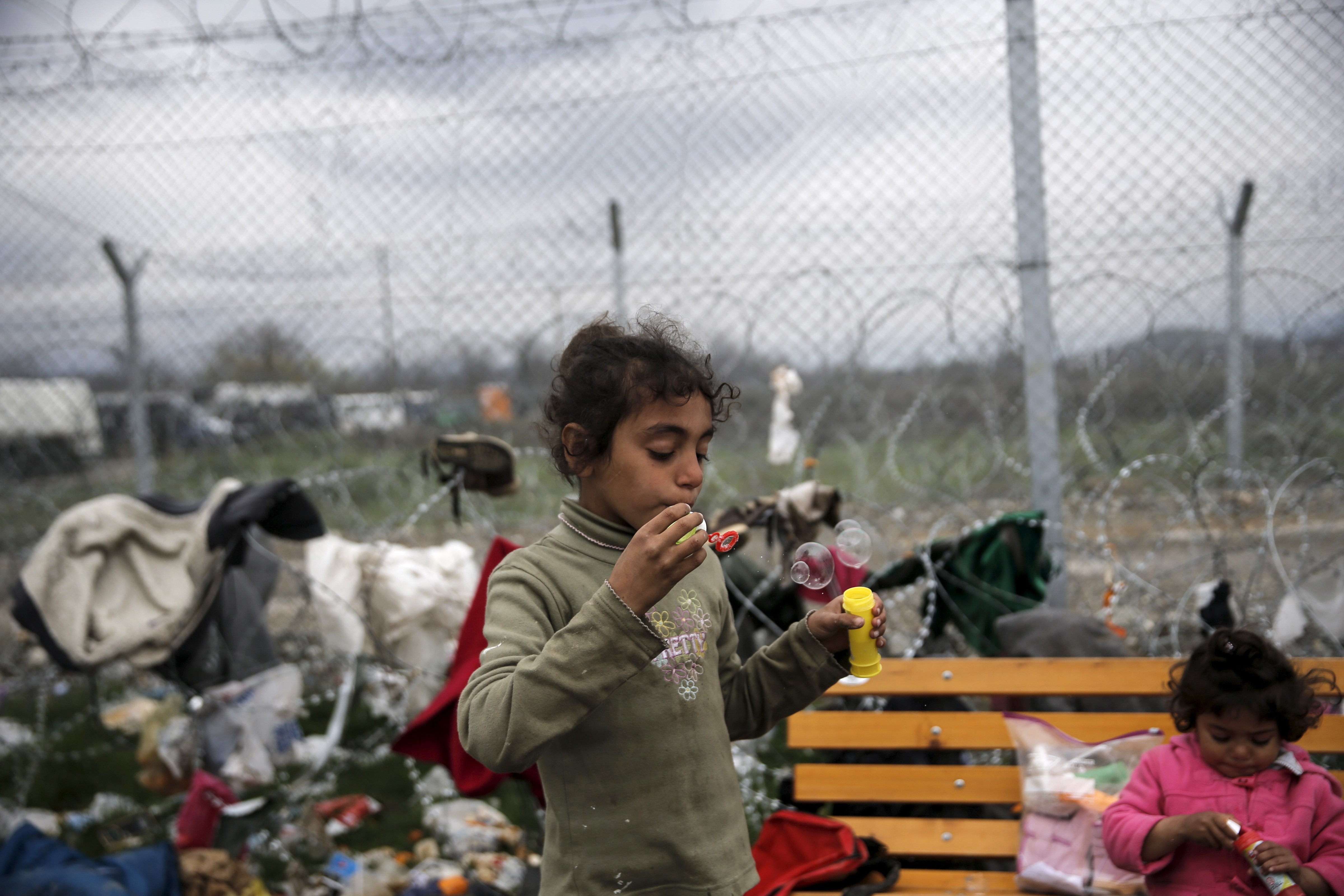 A Syrian refugee girl blows soap bubbles next to the border fence at the Greek-Macedonian border, at a makeshift camp for refugees and migrants near the village of Idomeni, Greece March 16, 2016 (Alkis Konstantinidis—Reuters)