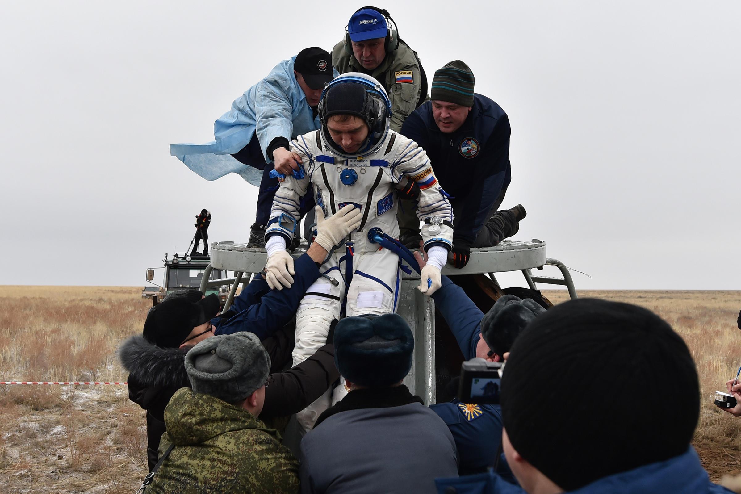 Ground personnel help International Space Station crew member Sergei Volkov of Russia get out of the Soyuz TMA-18M space capsule after landing in Kazakhstan, on March 2, 2016.