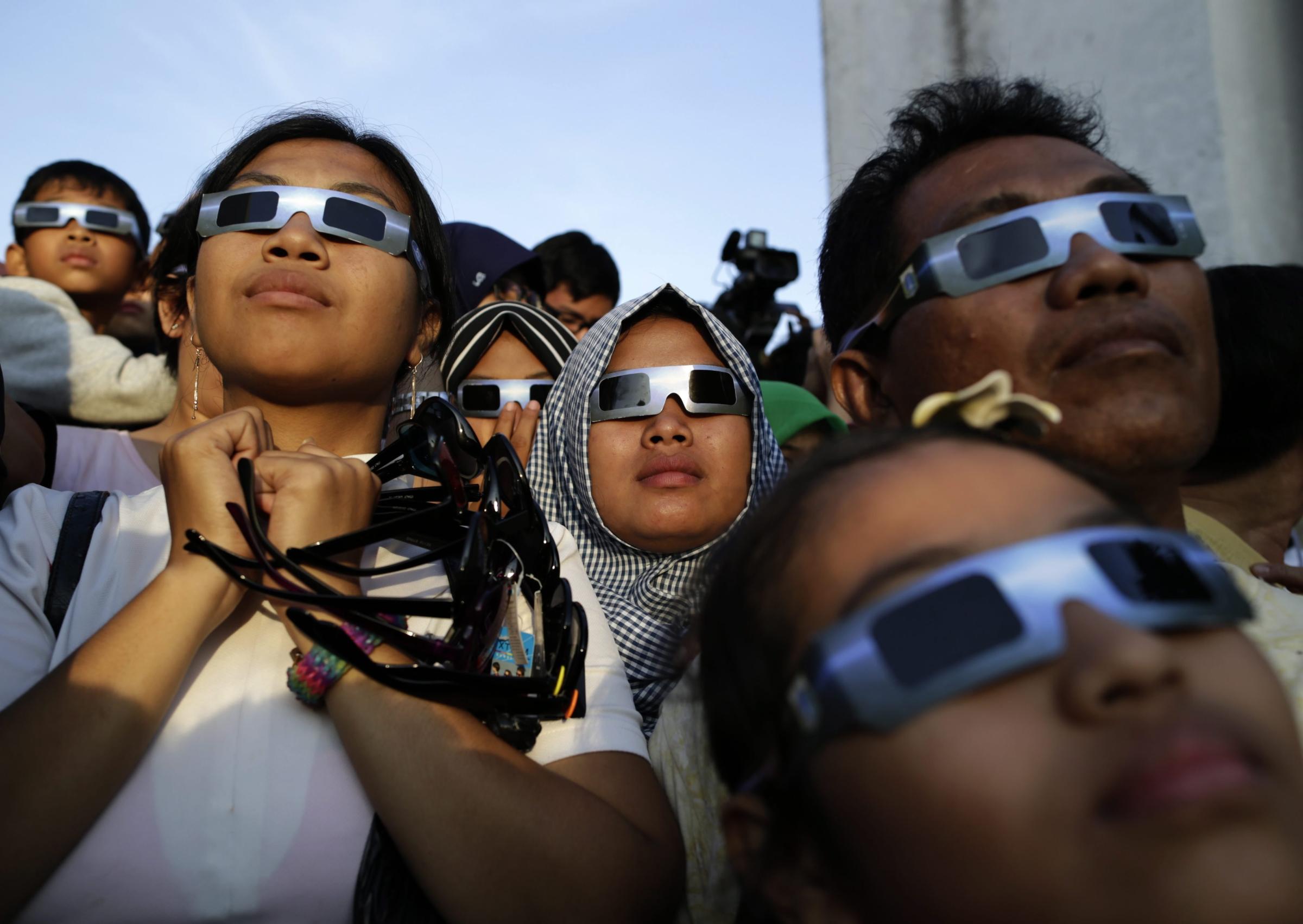 Indonesian residents wear eclipse glasses to watch a solar eclipse outside a planetarium in Jakarta, on March 9.