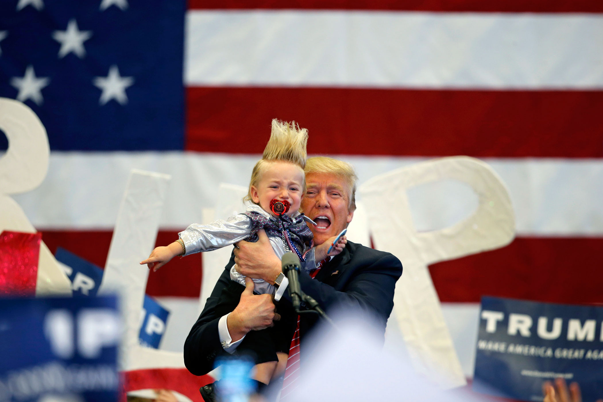 Republican presidential candidate Donald Trump holds up a child he pulled from the crowd as he arrives to speak at a campaign rally in New Orleans, Friday, March 4, 2016. (AP Photo/Gerald Herbert)
