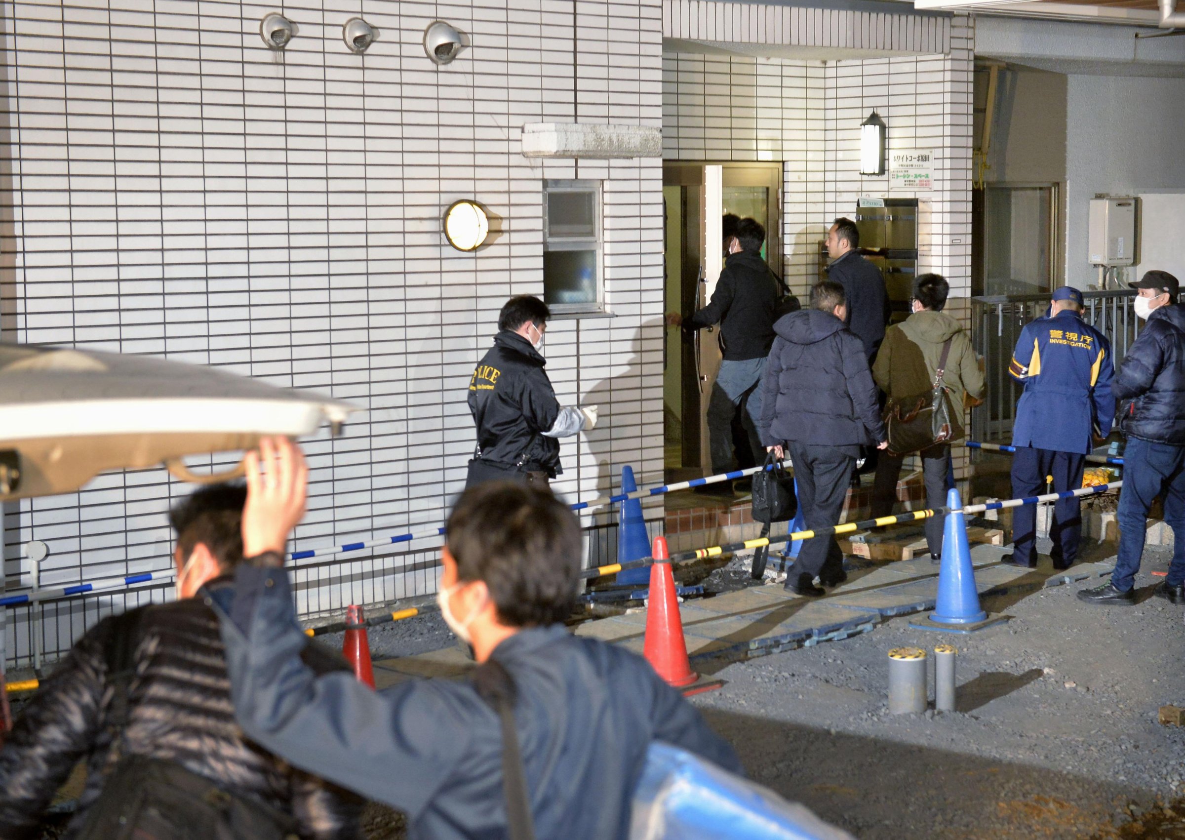 Police officers arrive for investigation of the apartment of abduction suspect Kabu Terauchi in Tokyo on March 28, 2016.