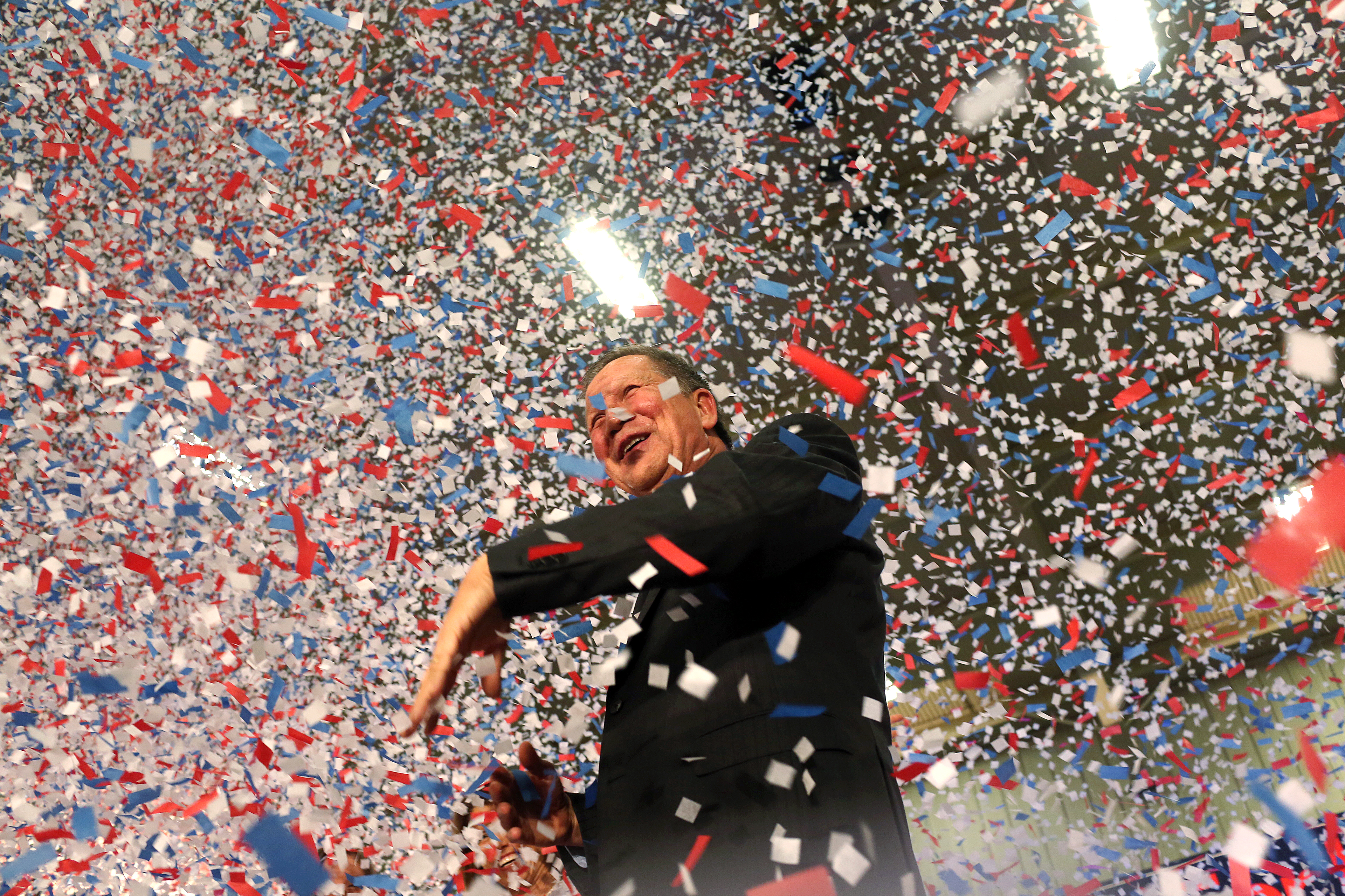 Republican presidential candidate, Ohio Gov. John Kasich waves confetti out of his way after giving his victory speech at Baldwin-Wallace University in Berea, Ohio on March 15, 2016.