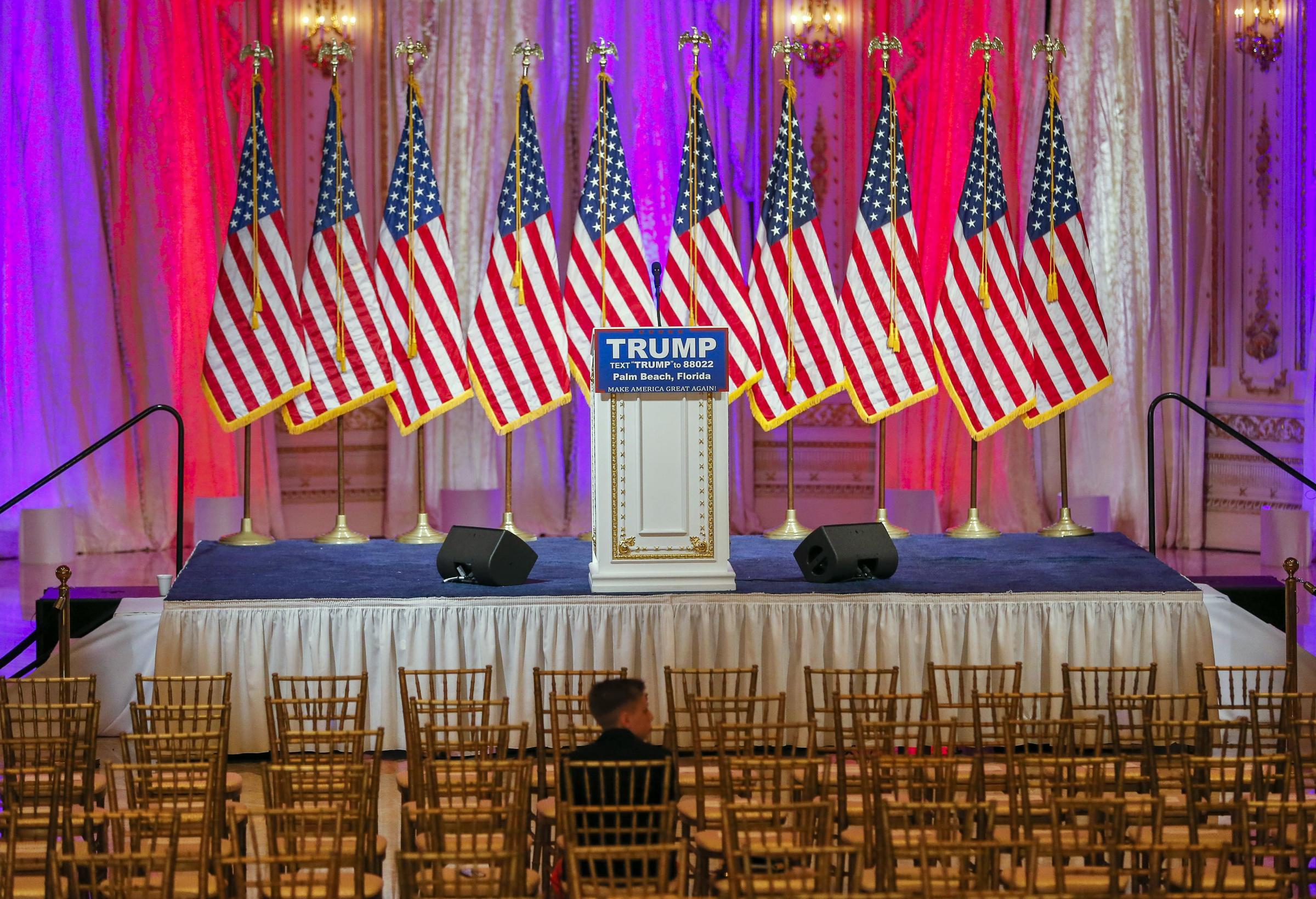 A boy sits near the stage where Republican presidential candidate Donald Trump is scheduled to participate in a news conference inside a ballroom at the Mar-a-Lago Club in Palm Beach, Fla. on March 15, 2016.