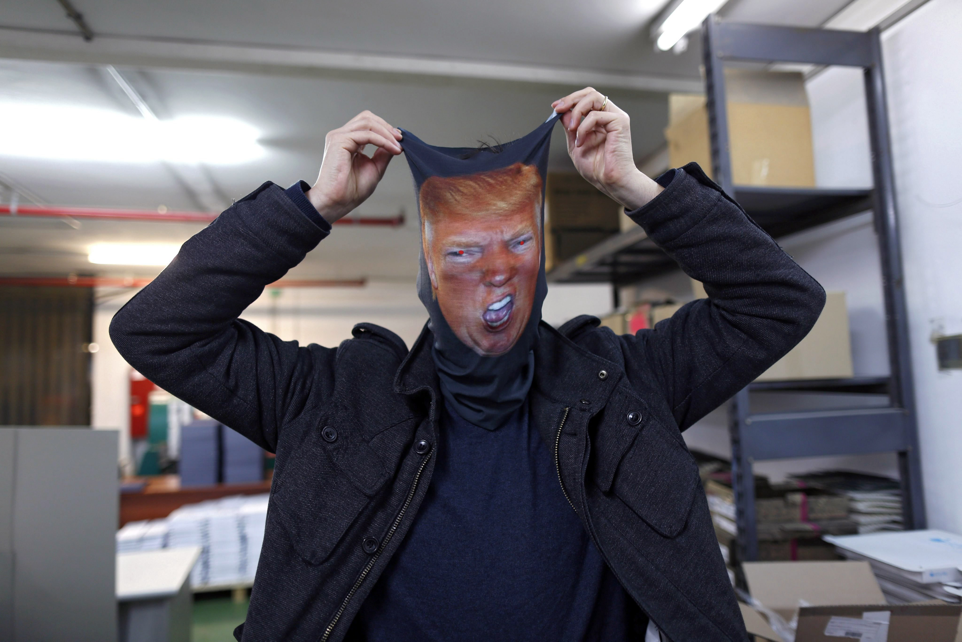Dror Mangel poses with a printed mask showing the likeness of Donald Trump in his shop in Tel Aviv on March 17, 2016.
