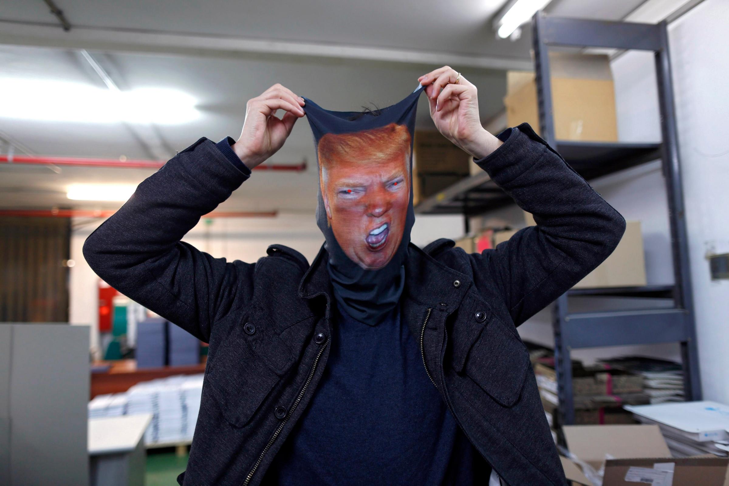 Dror Mangel poses with a printed mask showing the likeness of Donald Trump in his shop in Tel Aviv, Israel on March 17, 2016.