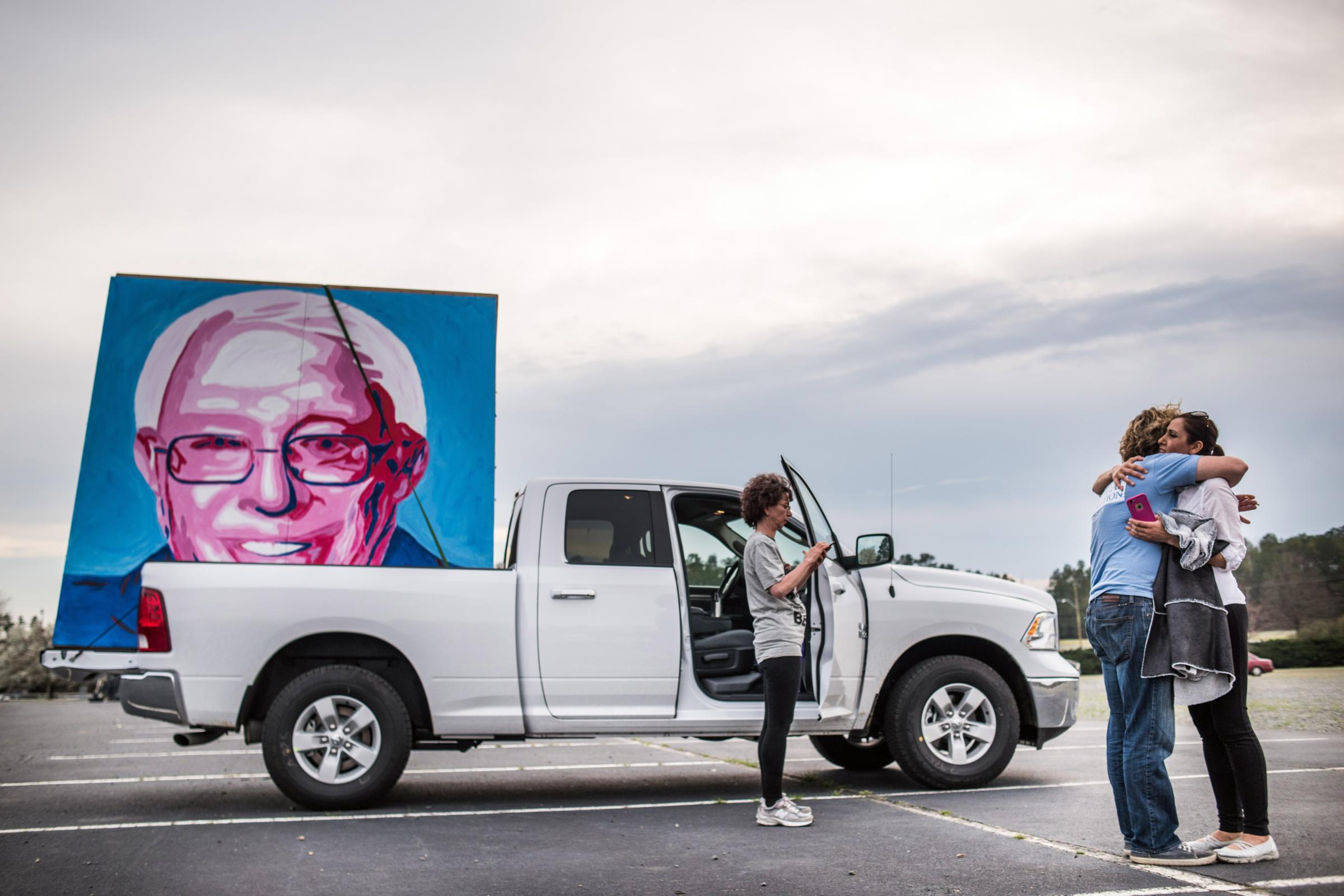 Joseph Kelly, left, hugs Farzaneh Rezaei after loading his large painting showing the likeness of Bernie Sanders into a truck following a campaign rally on March 14 in Charlotte, N.C.