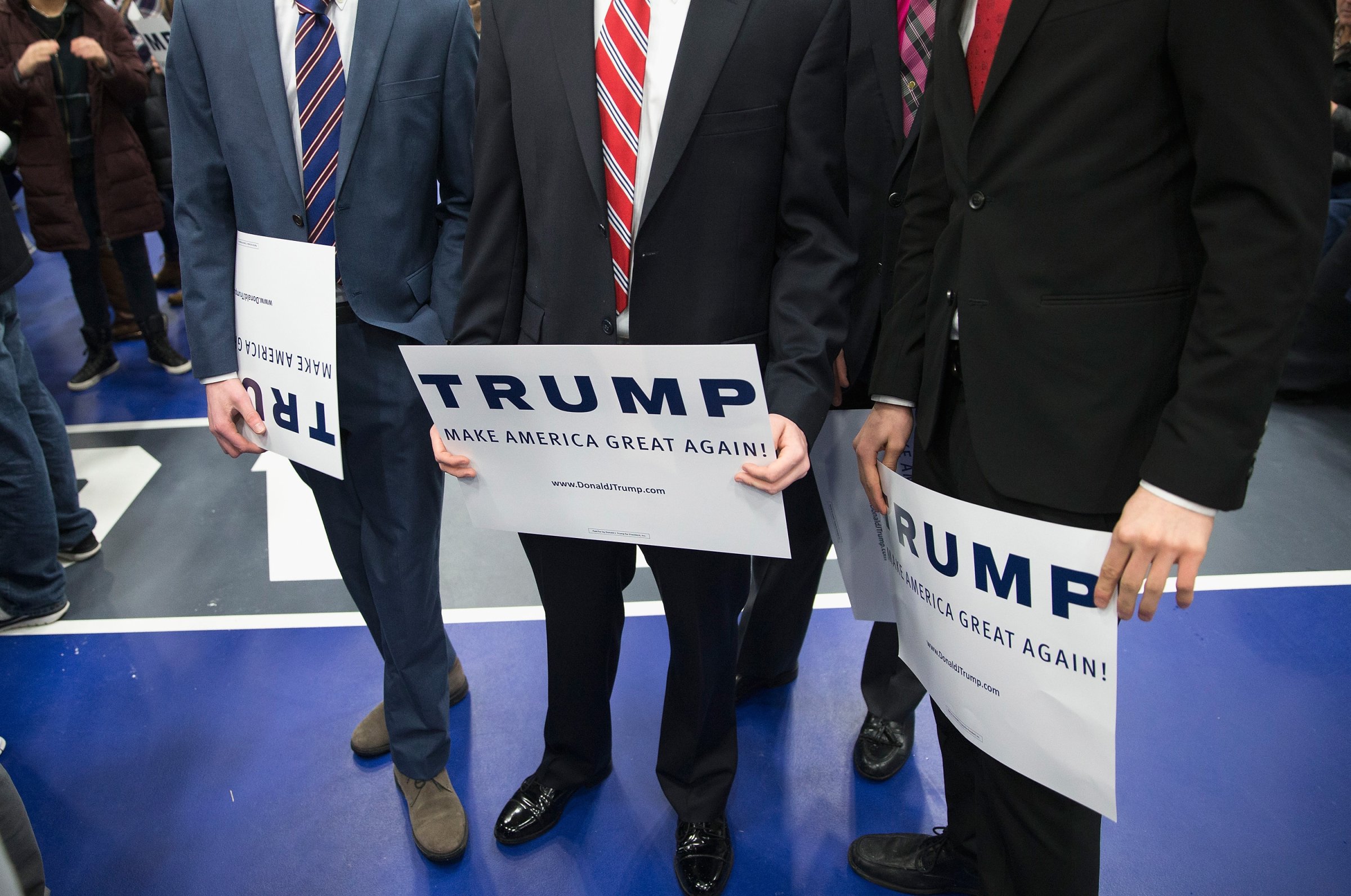 Men hold signs while waiting for Republican presidential candidate Donald Trump to arrive for a rally at Macomb Community College in Warren, Mich., on March 4, 2016.