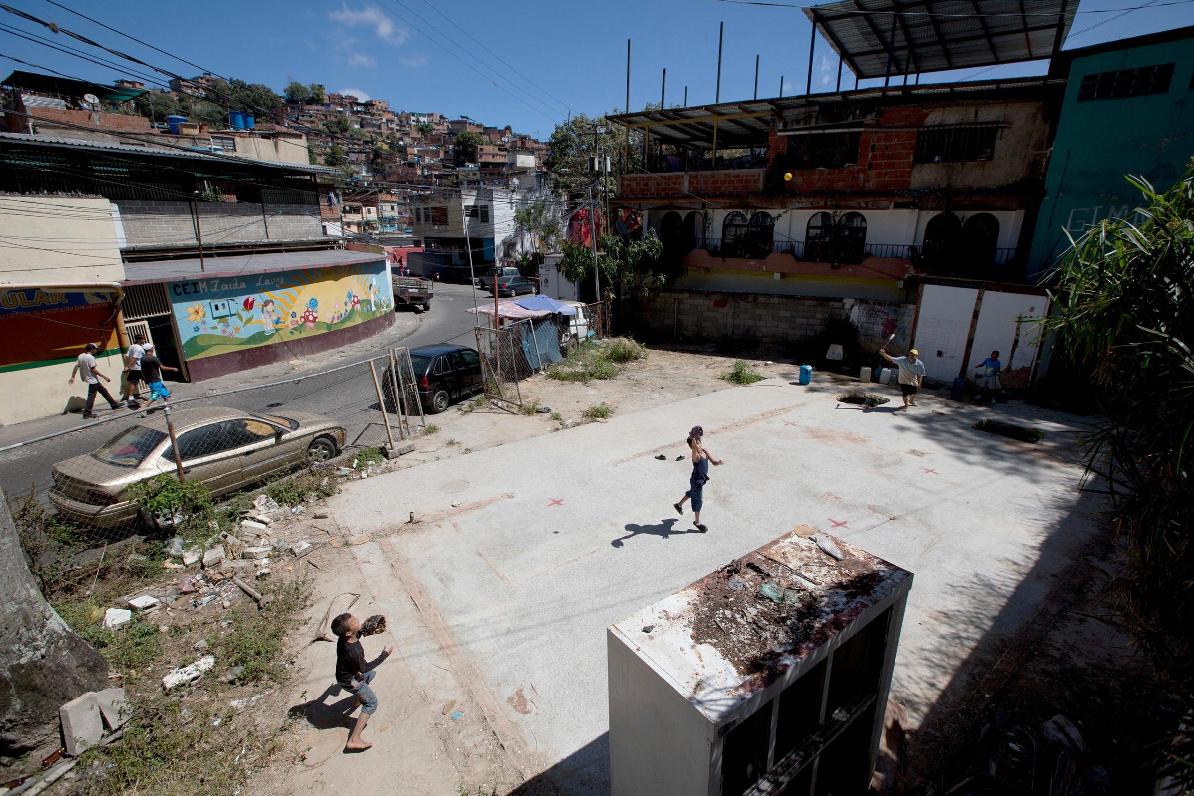 A man and his sons play baseball as they collect drinking water from an abandoned social center in the La Dolorita neighborhood of Caracas, Venezuela, Feb. 10, 2016. Officials say the water shortage is due to a severe drought caused by the El Nino.