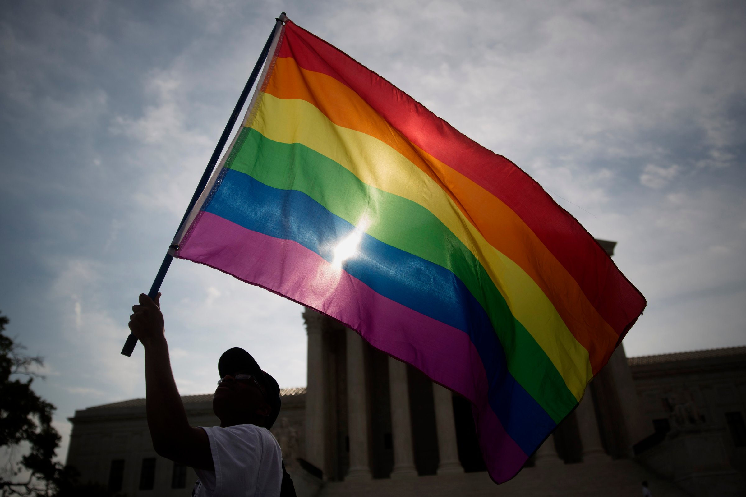 Carlos McKnight, from Washington, D.C., waves a rainbow colored flag outside the U.S. Supreme Court in Washington, D.C., U.S., on Friday, June 26, 2015.