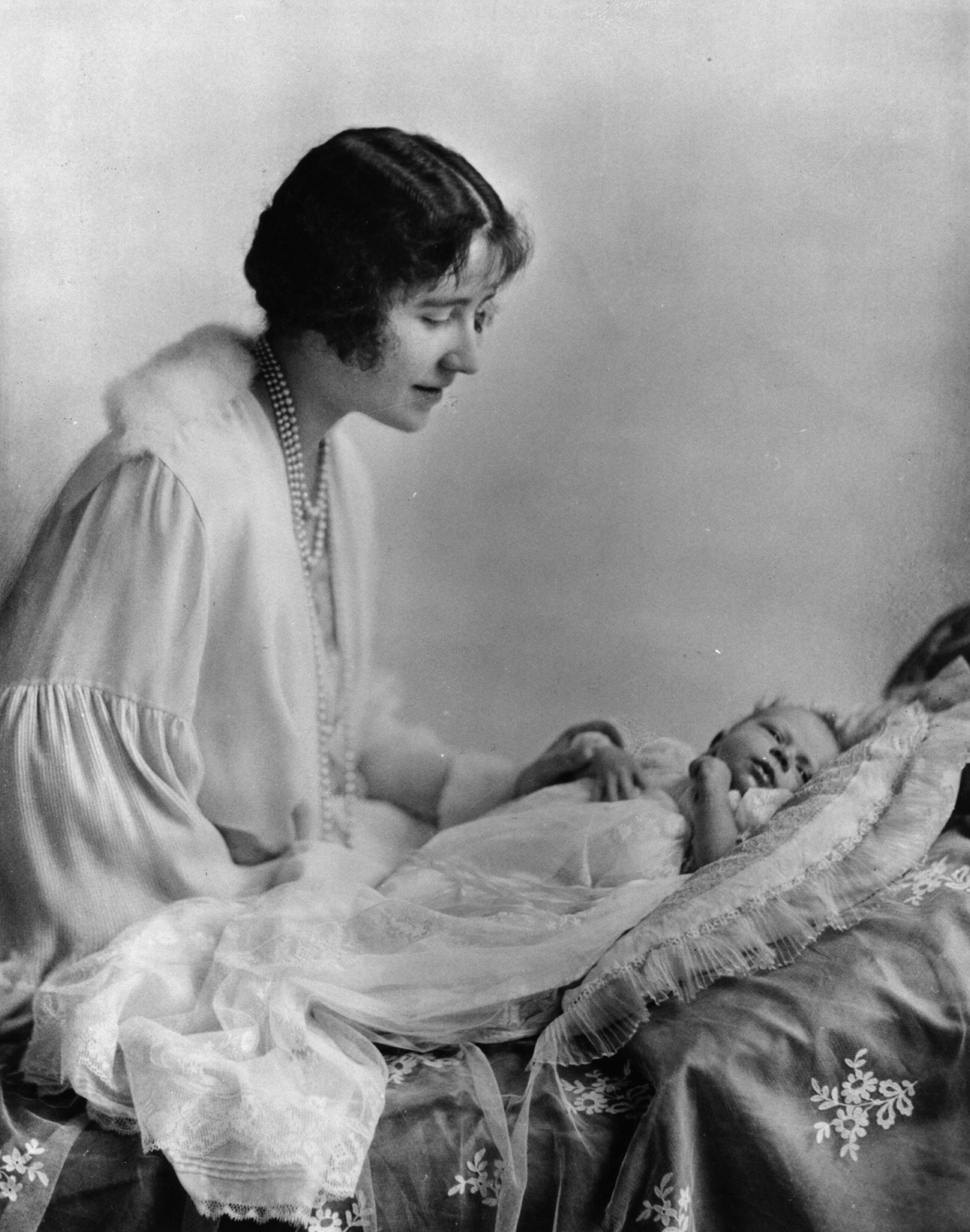 Elizabeth, Duchess of York (1900 - 2002), looking at her first child, future Queen, Princess Elizabeth. May 1926.
