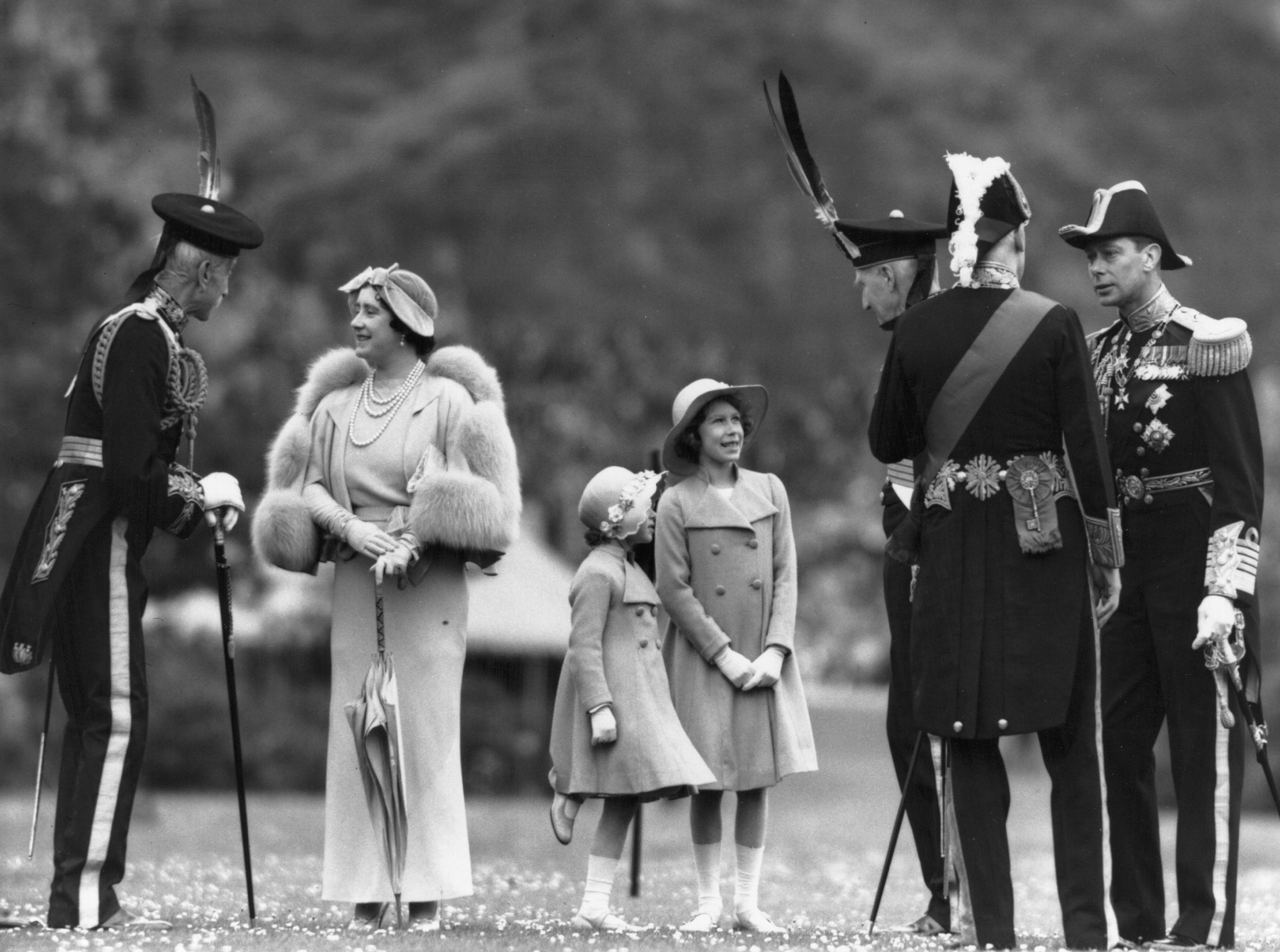Queen Elizabeth talking to Lord Elphinstone during an inspection of the Royal Company of Archers at the Palace of Holyroodhouse, Edinburgh. Her husband King George VI is on the right; Princesses Elizabeth and Margaret Rose are in the center. July 1937.