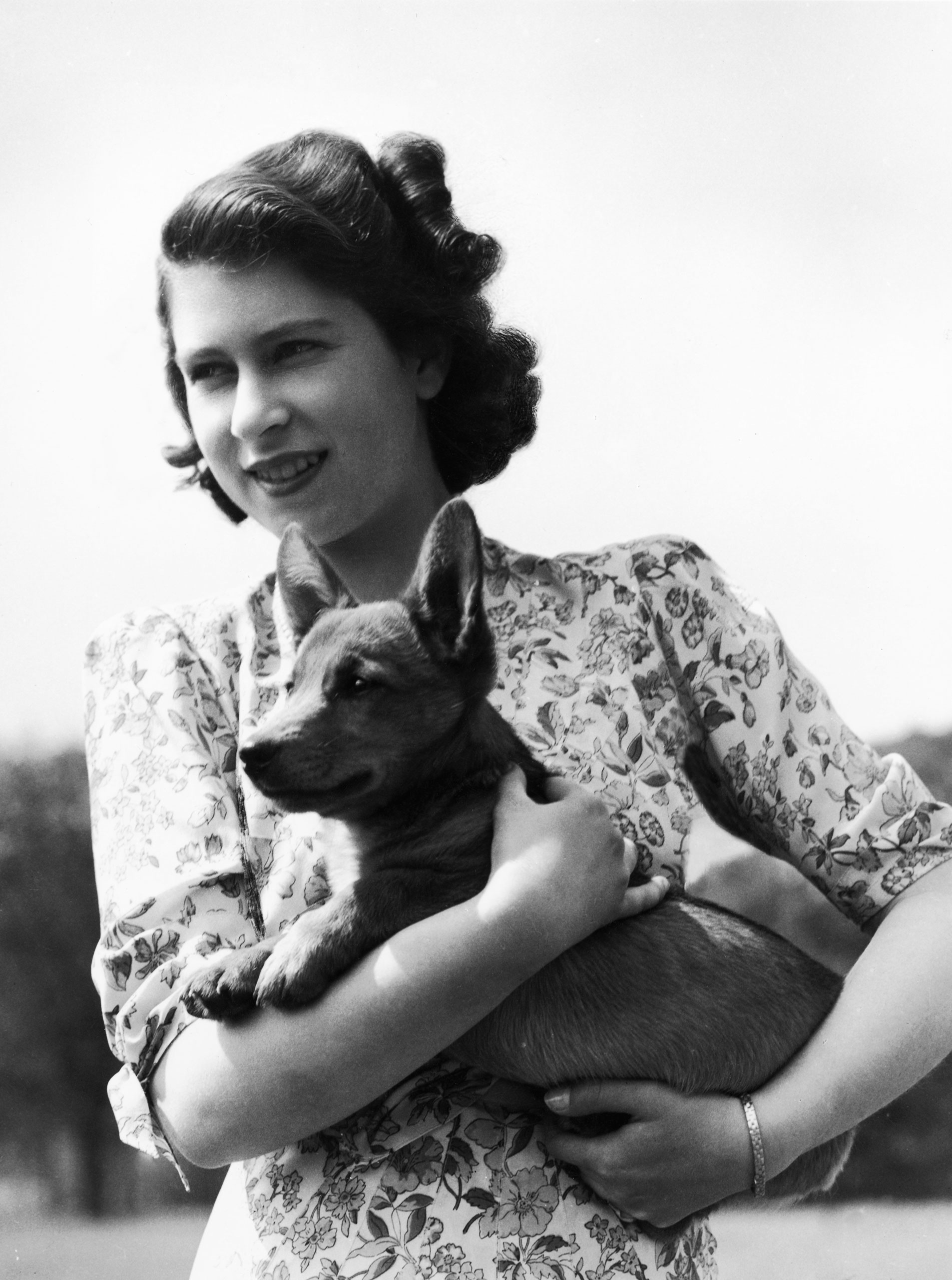 Princess Elizabeth holding Sue, a corgi pup, in the grounds of Windsor Castle, Berkshire, May 30, 1944.