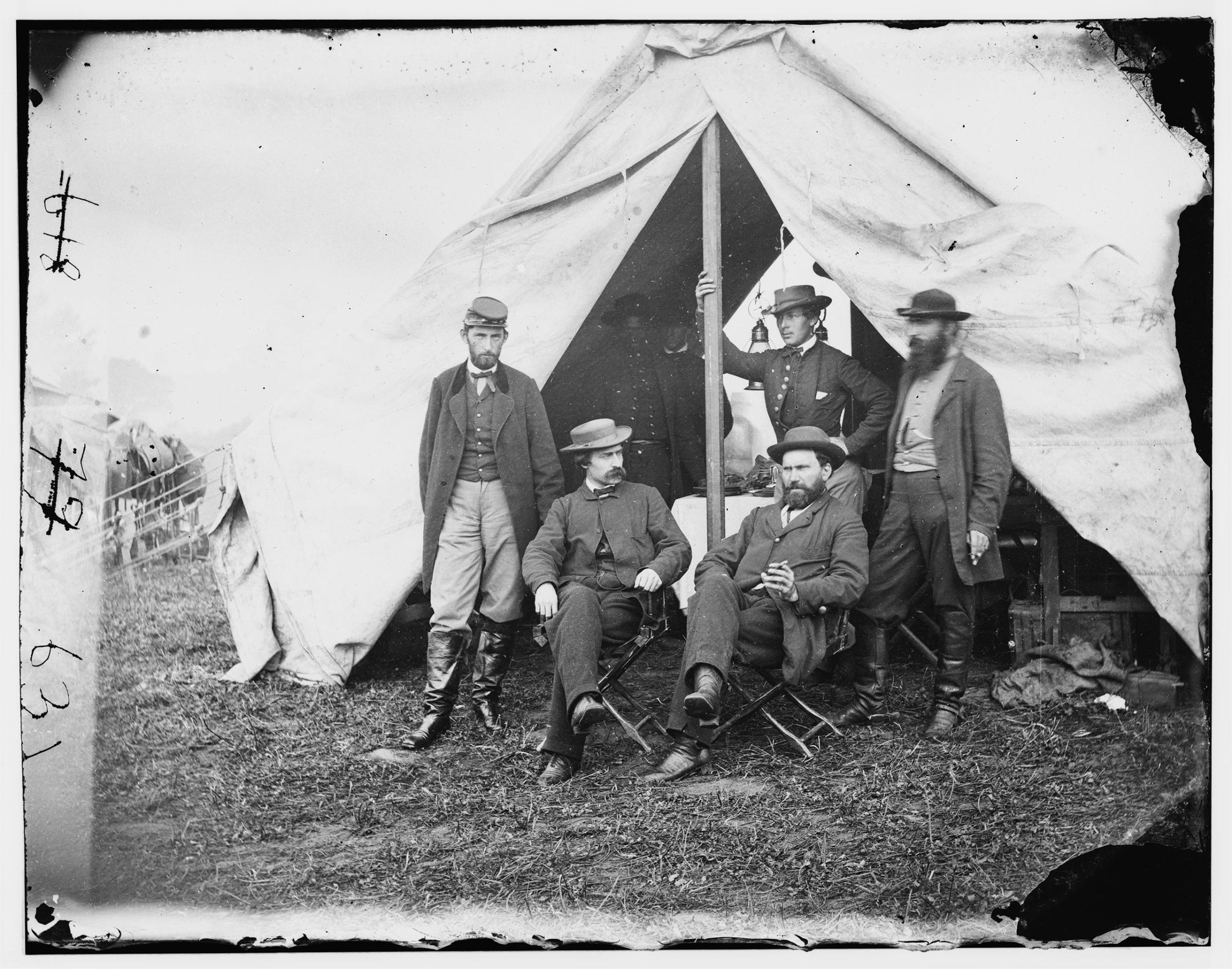 Detective Allan Pinkerton (sitting on the right) at Antietam during the Civil War. Standing behind Pinkerton holding the tent pole is believed to be Kate Warne, the first female detective in America, dressed as a man.
