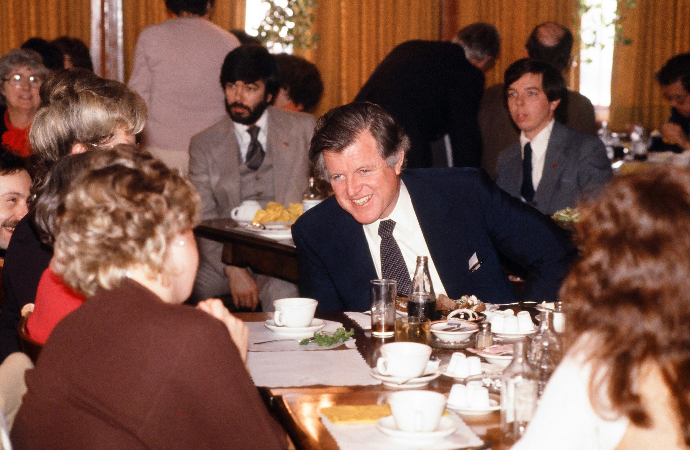 Senator Ted Kennedy laughs as he shares a meal with unidentified supporters at a restaurant during his campaign tour for the Democratic nomination for president, 1980.