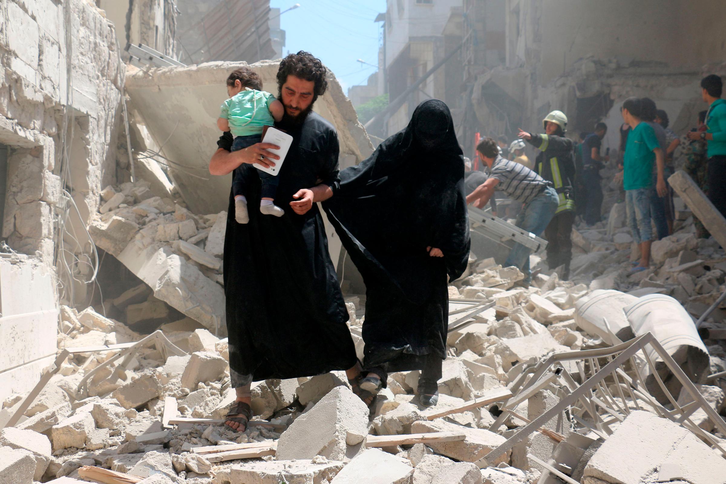 A family walks amid the rubble of destroyed buildings following a reported airstrike on a rebel-held neighborhood in Aleppo, Syria, April 28, 2016.