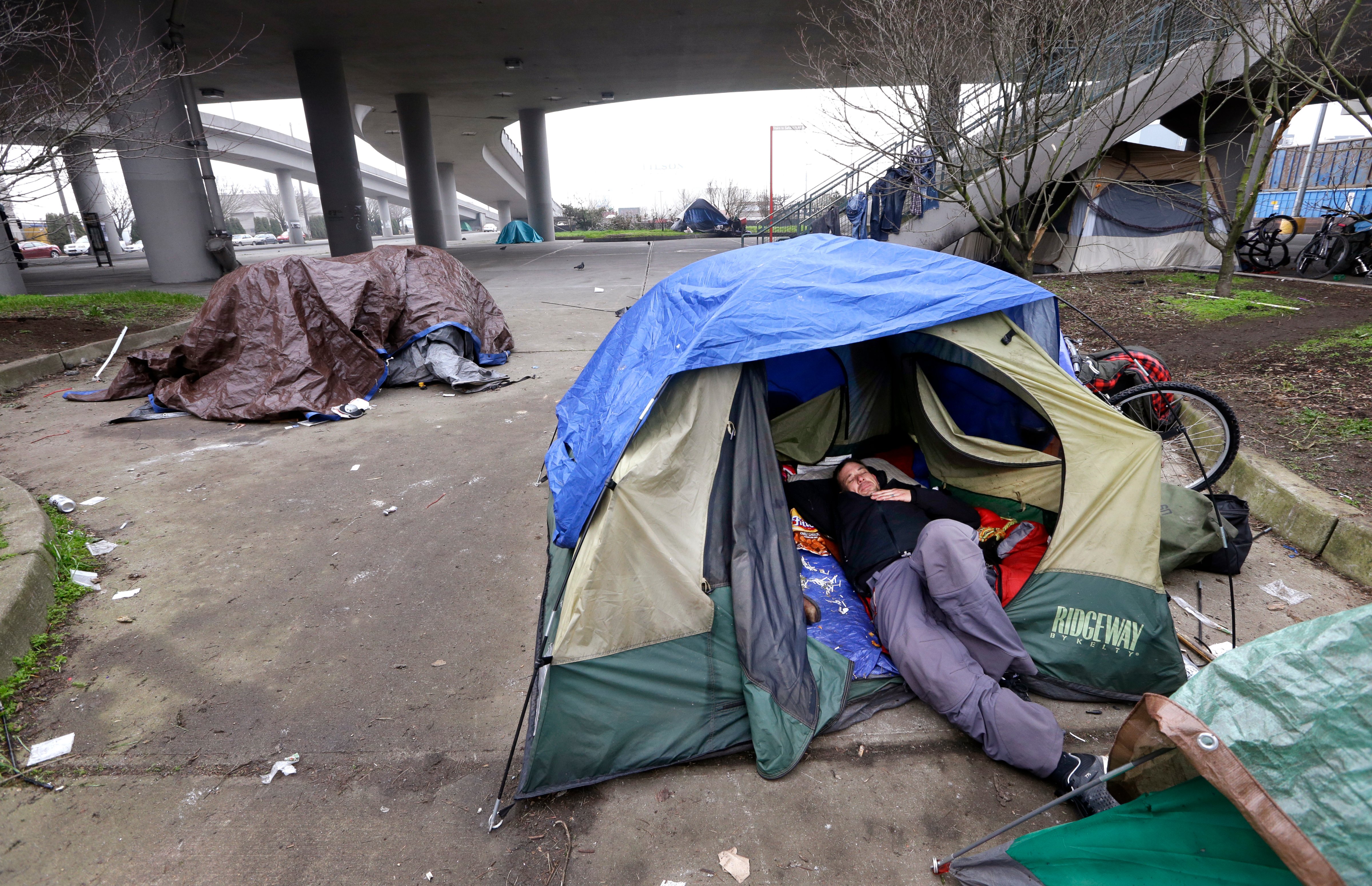 A man lies in a tent with others camped nearby, under and near an overpass in Seattle on Tuesday, Feb. 9, 2016. Seattle has the third-highest number of homeless people in the U.S. (Elaine Thompson—AP)