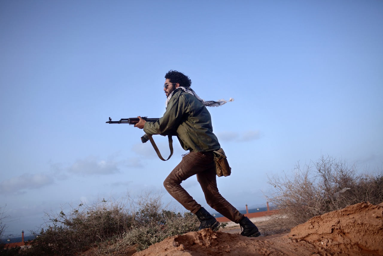 An Anti-Qaddafi rebel, armed with Kalashnikov assault rifle, clears an area near the front line in Bin Jawad in 2011.