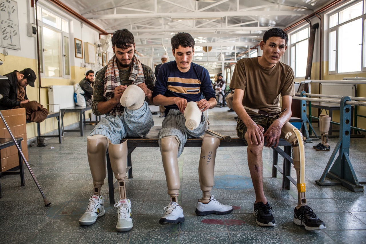 Afghan National Army soldiers with injuries and amputations adjust their prostheses between sessions at a therapy center.