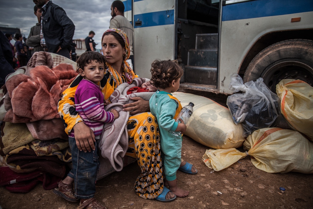 A Syrian Kurdish family waits to be taken to a Turkish shelter after fleeing shelling in Yumurtalik, Turkey.