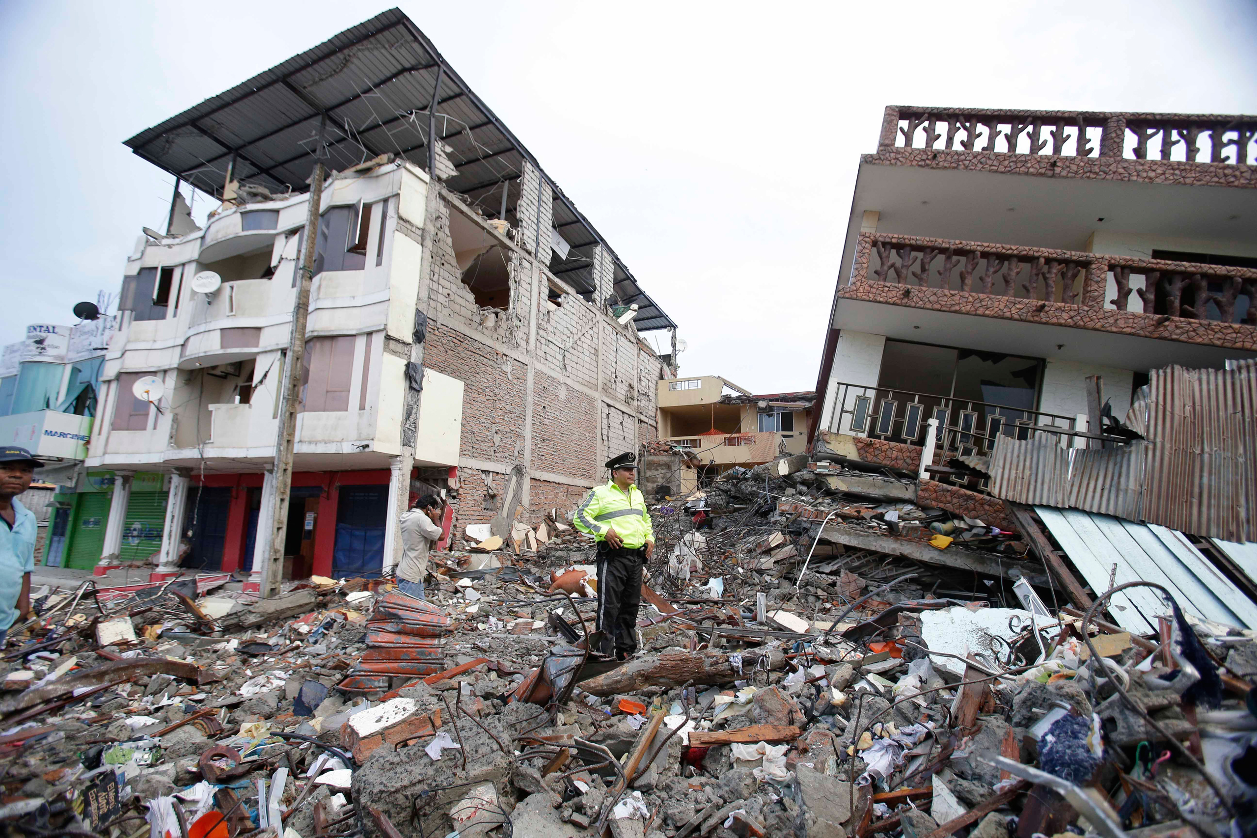 A police officer stands on debris, next to buildings destroyed by an earthquake in Pedernales, Ecuador, on April 17, 2016.