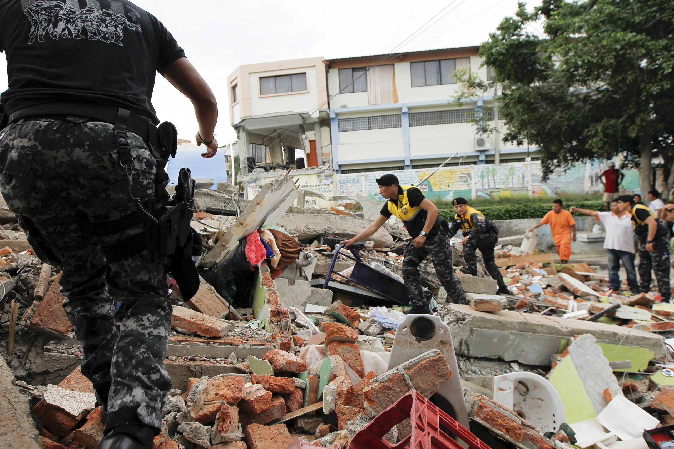 Red Cross members, military and police officers work at a collapsed area after an earthquake struck Manta, off Ecuador's Pacific coast, on April 17, 2016.