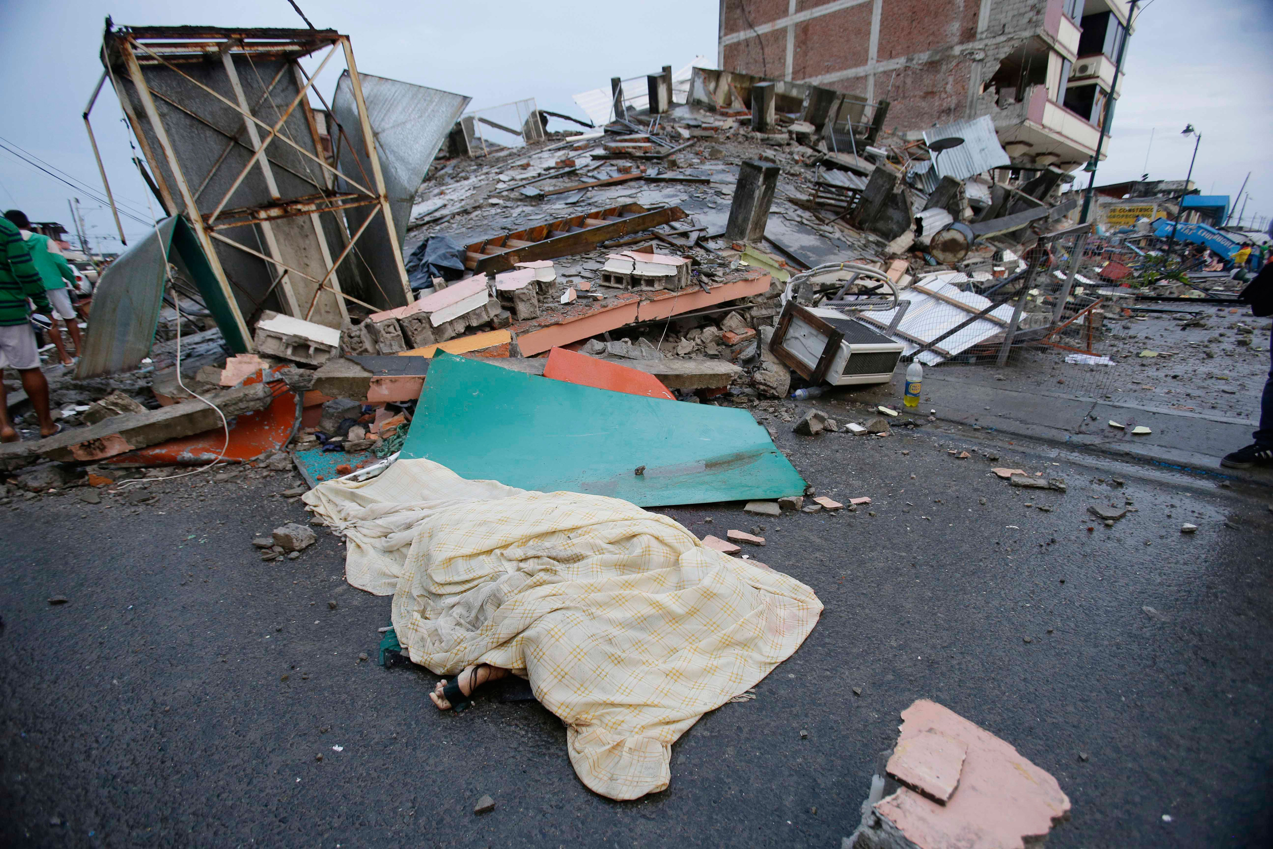 A body covered by sheet lies next to buildings destroyed by an earthquake in Pedernales, Ecuador, on April 17, 2016. The strongest earthquake to hit Ecuad