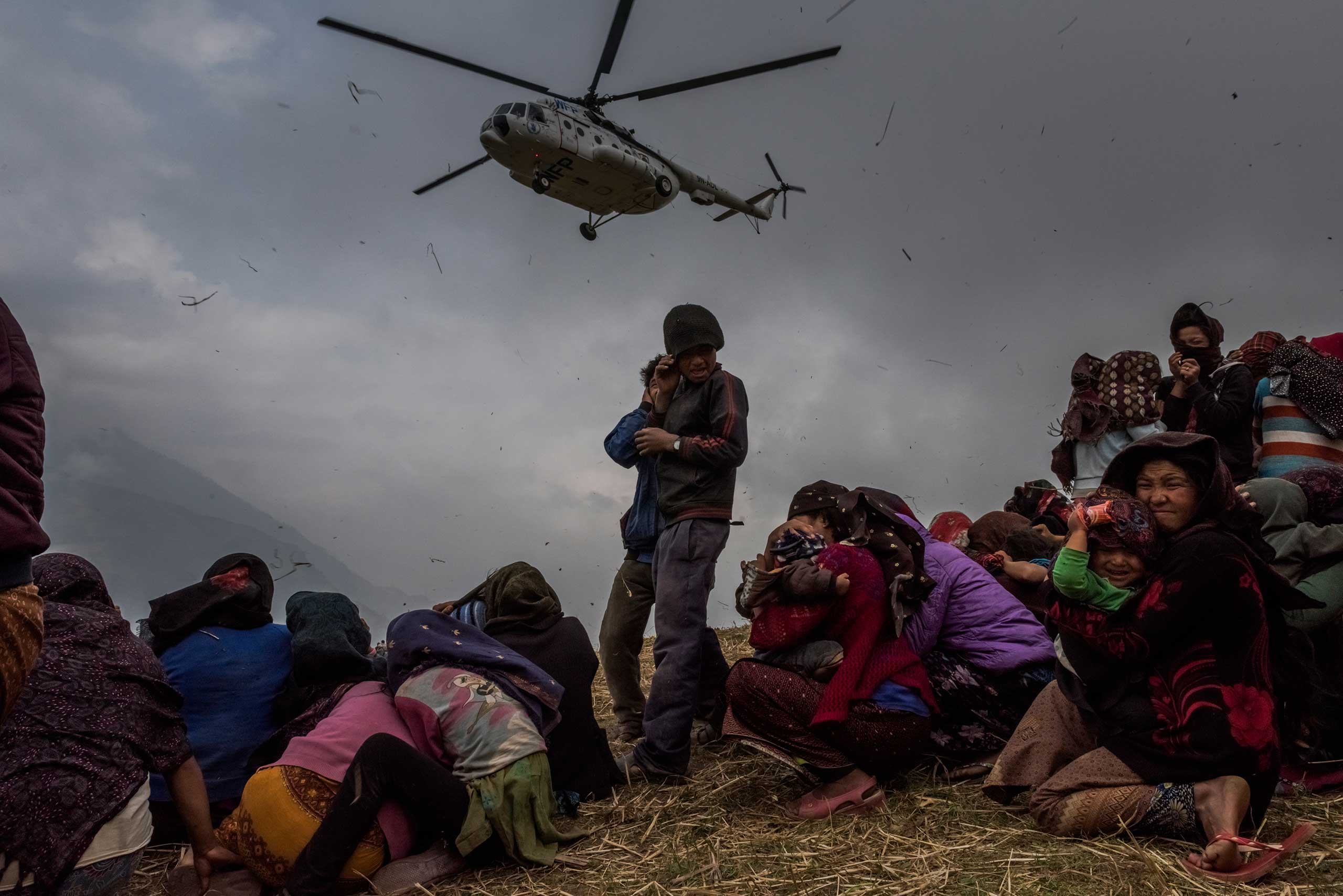 Nepalese villagers turn away from the downdraft of a helicopter delivering relief supplies to Gumda, a remote hillside village in Nepal. The mountainous terrain meant many of the earthquake-affected villages could be reached only by air, or by hours or days on foot. May 9, 2015.