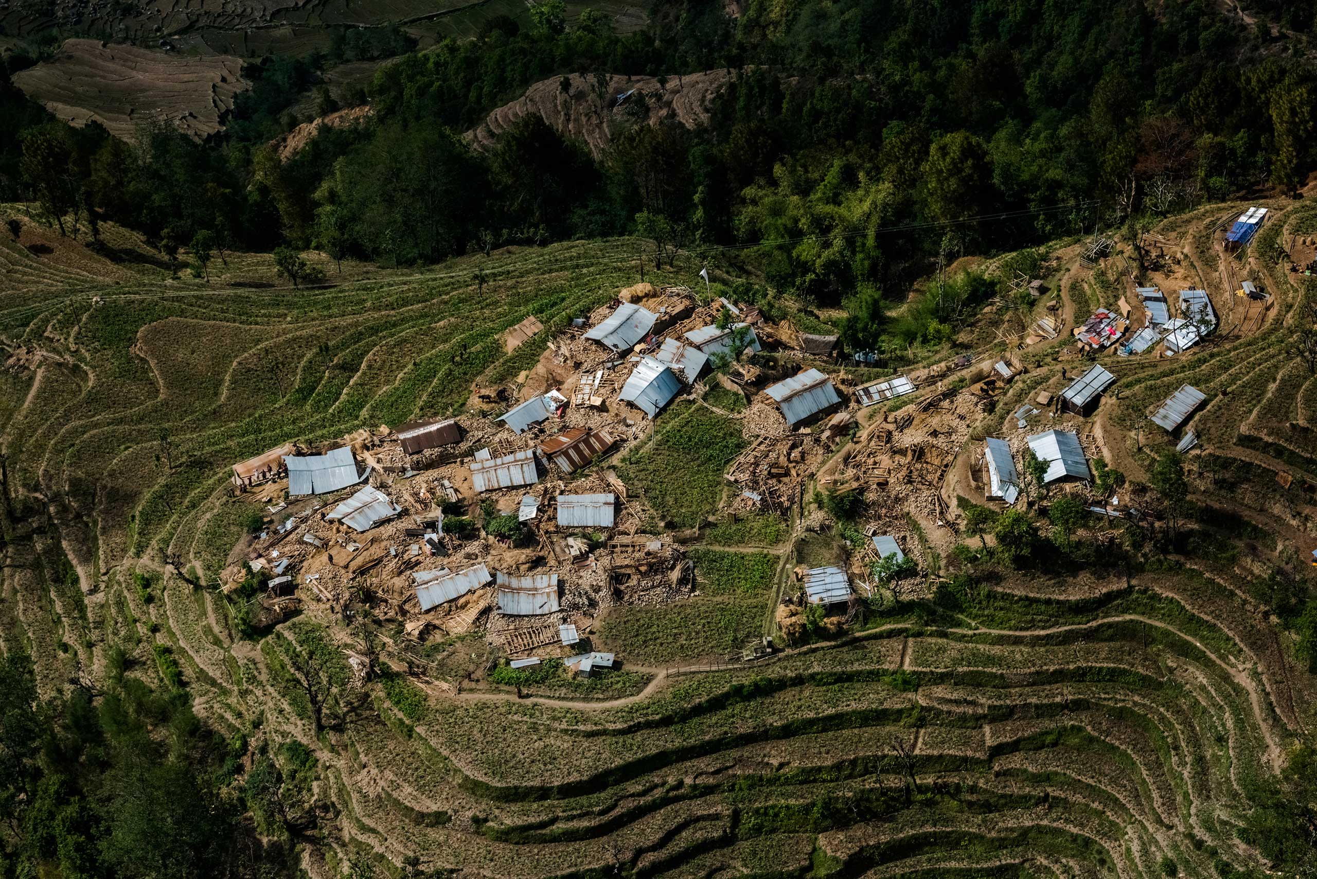 Earthquake-flattened homes are seen from an Indian military helicopter above a village in the Nuwakot district in Nepal. The helicopter was unable to find a stable or large enough area to land, so it hovered above the narrow hillside farmland, and army personnel threw food from the aircraft. May 1, 2015.