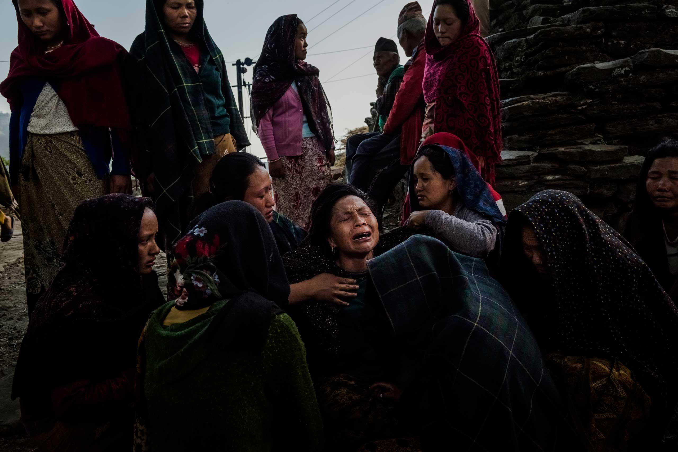 Saainli Gurung is consoled by neighbors and family after the body of her son Pur Bahadur Gurung, 26, was discovered under a trail leading through the rubble of houses in Barpak, Nepal. May 5, 2015.