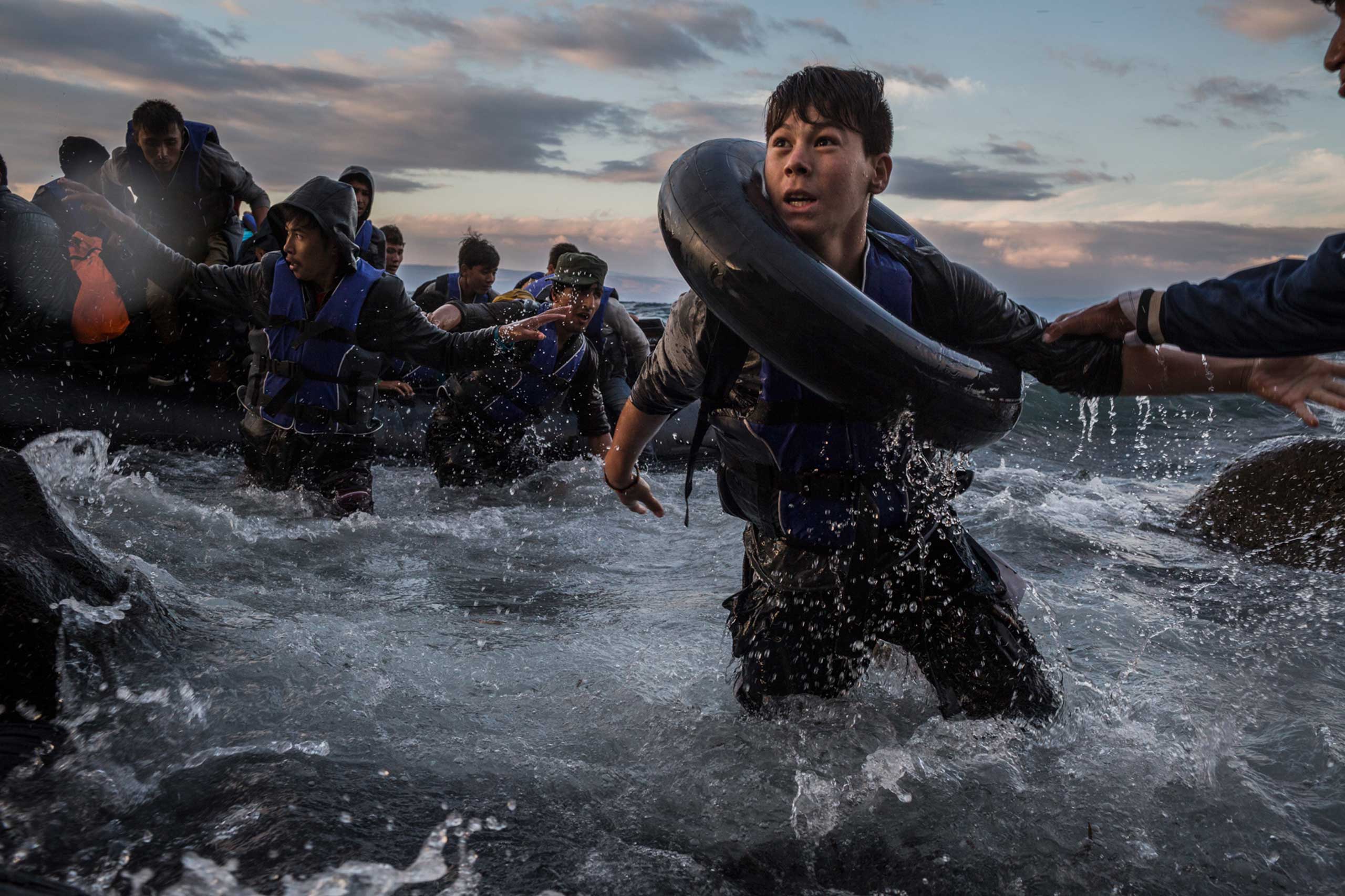 After battling rough seas and high winds from Turkey, migrants arrive by rubber raft on a jagged shoreline of the Greek island of Lesbos. Fearing capsize or puncture, some panicked and jumped into the cold water in desperation to reach land. This young boy made it, unlike hundreds of others. Oct. 1, 2015.