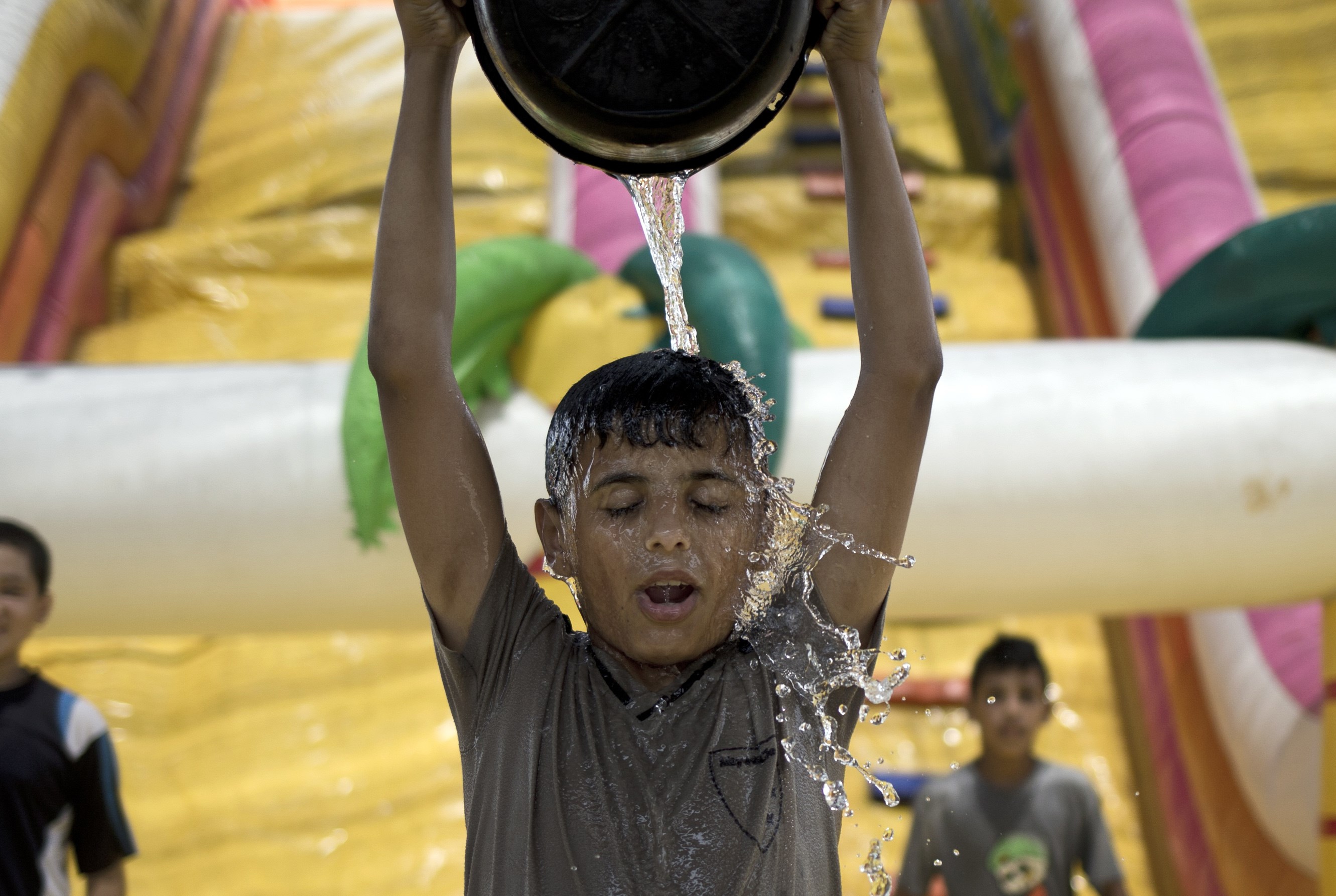 A Palestinian boy empties a bucket of water on his head in Gaza City on Aug. 3, 2015, during a sweltering heat wave. (Mohammed Abed—AFP/Getty Images)