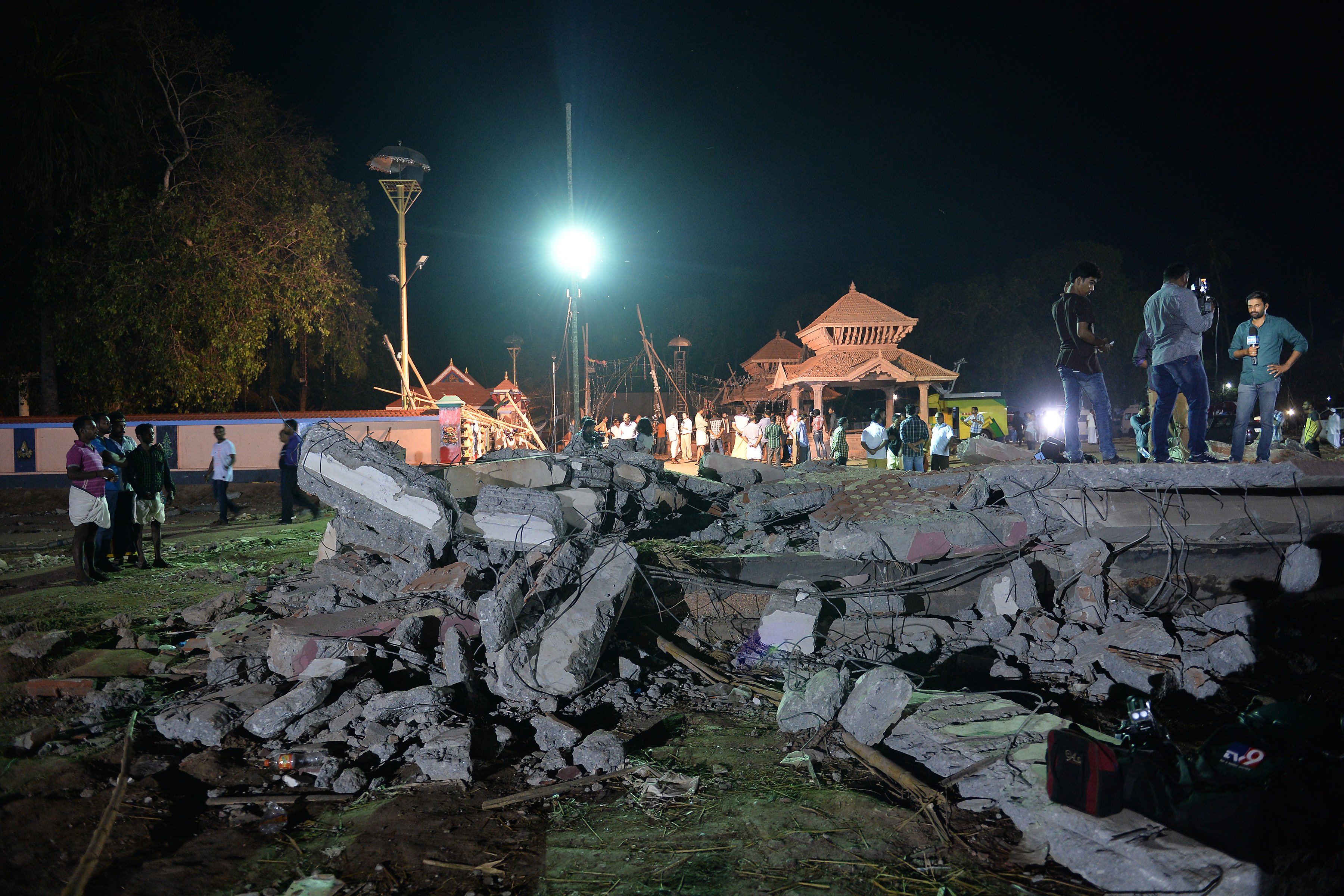 Onlookers stand amid the debris in the aftermath of the deadly fire explosion that rocked Puttingal Temple in Paravoor, nearly 40 miles (60 km) northwest of Thiruvananthapuram in Kerala state, India, on April 10, 2016 (Manjunath Kiran—AFP/Getty Images)