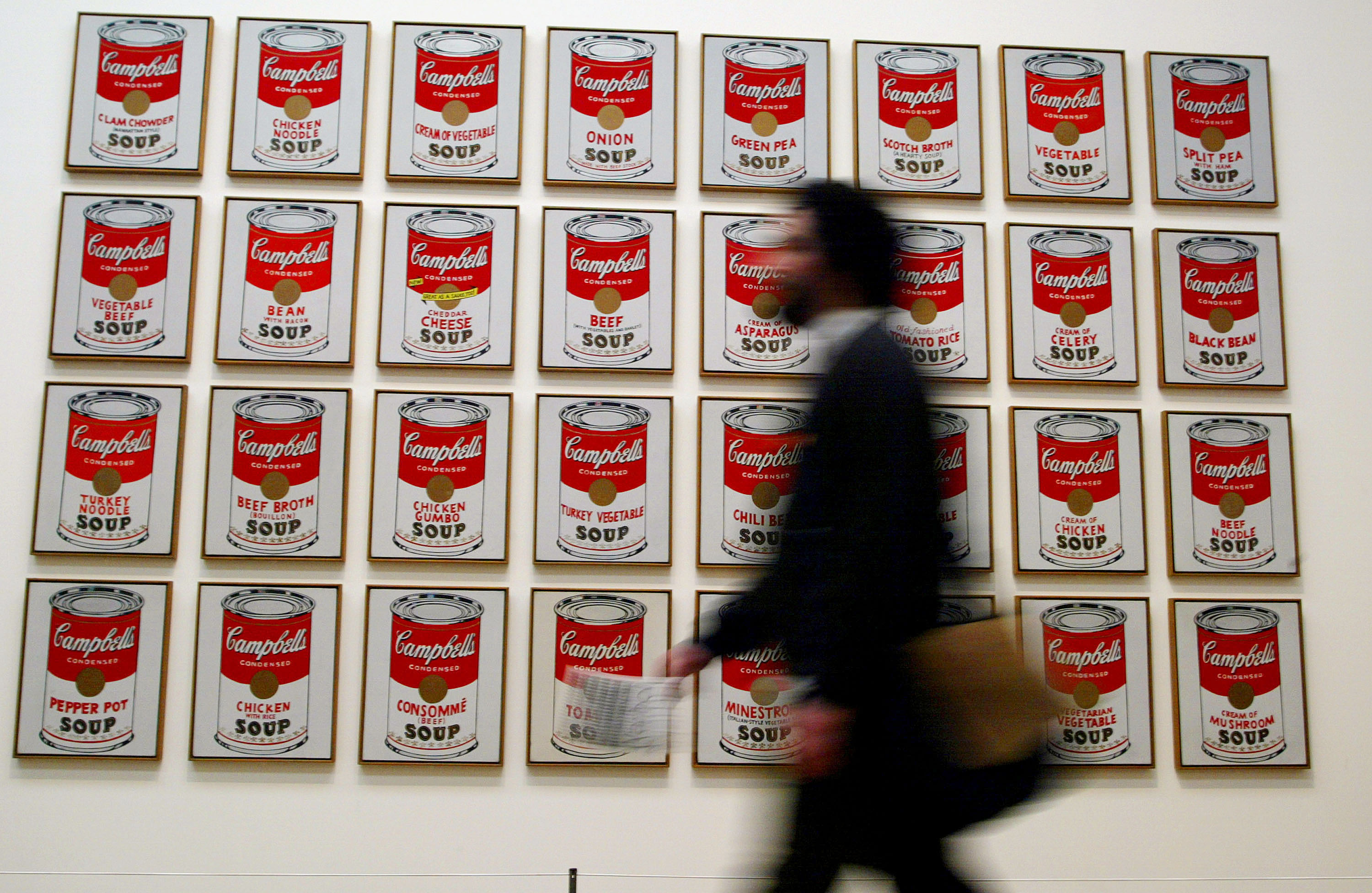 A spectator walks past "Campbells Soup Cans" created in 1962 by artist Andy Warhol at the Andy Warhol retrospective exhibition February 5, 2002 at the Tate Modern Gallery in London. (Sion Touhig—Getty Images)