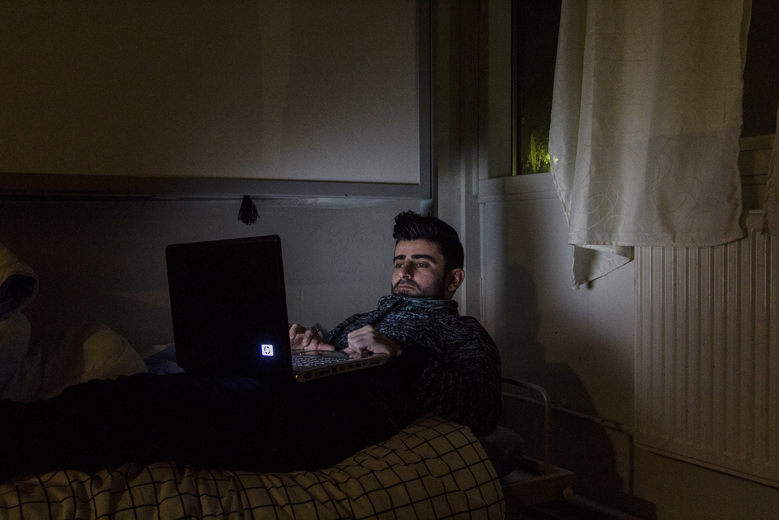 Qanie Nazari checks Facebook on the computer inside his room at the Sandholm Asylum Center. Though he can't read or write,  pictures help him navigate the site, Jan. 2016.