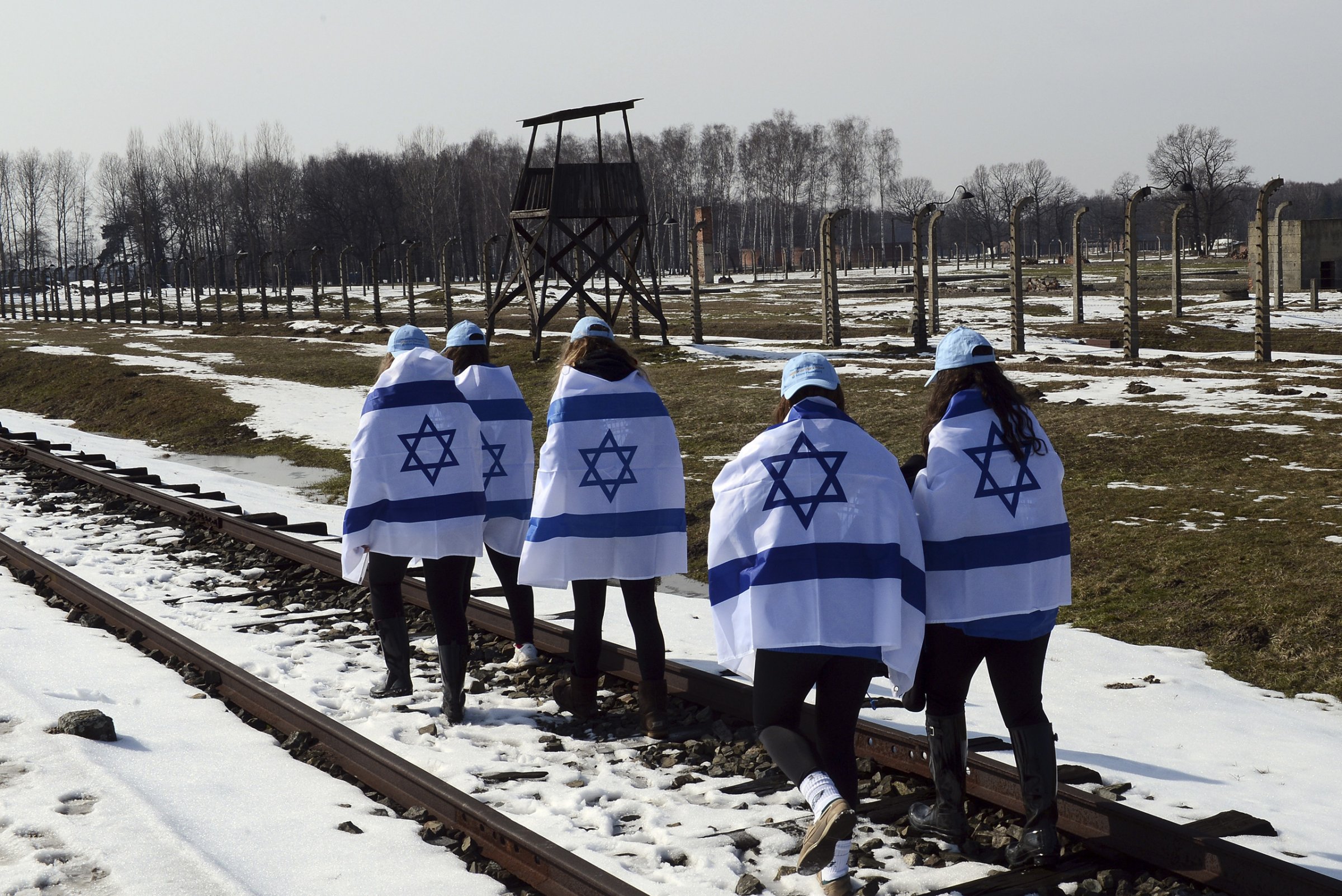 Participants of the annual "March of the Living" carry the Israeli flag wrapped around their shoulders as they walk along the rail road of the Auschwitz-Birkenau concentration camp in Oswiecim, Poland, April 8, 2013.