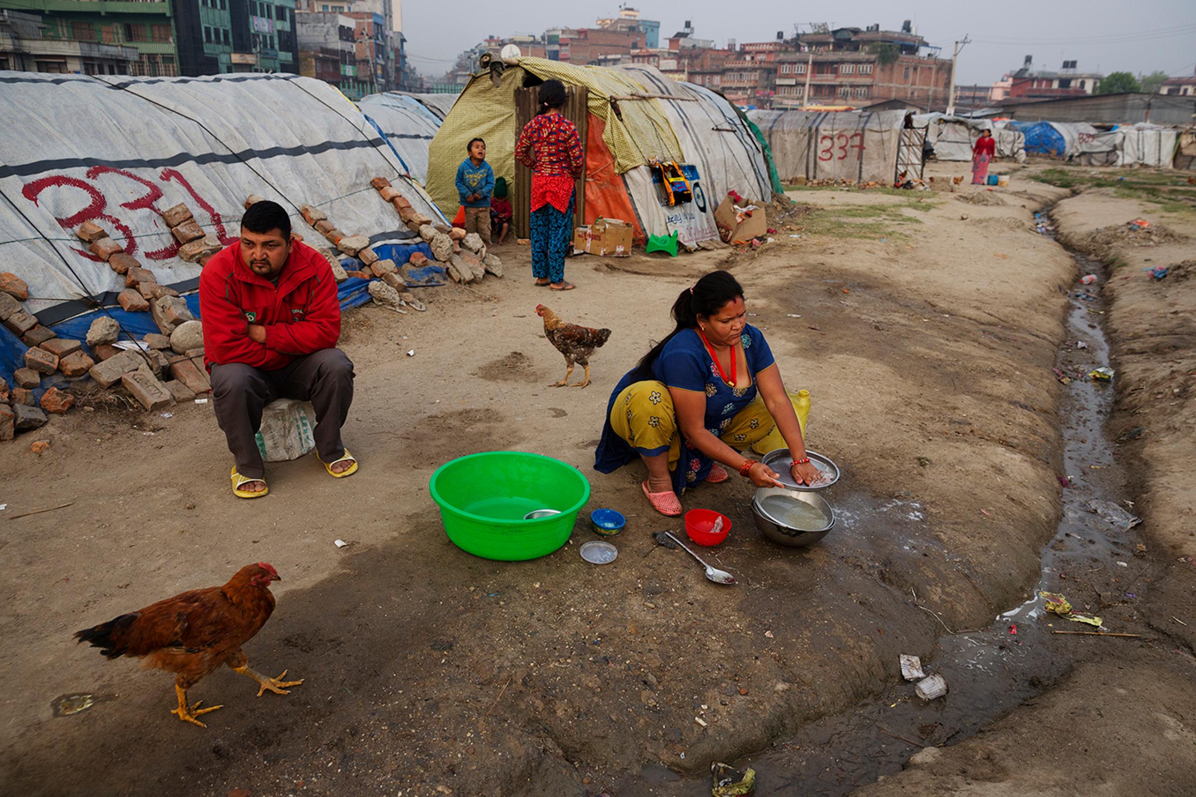 A family sits in an Informal tent encampment in central Kathmandu, Nepal. Approaching the first anniversary of the quakes of 2015, many people have been living in the squalid conditions of the camp for the past year. Some residents of the camp are from towns and villages in the region of Kathmandu, while others, some of whom are Nepalese migrant workers, are from more distant areas, March 31, 2016.