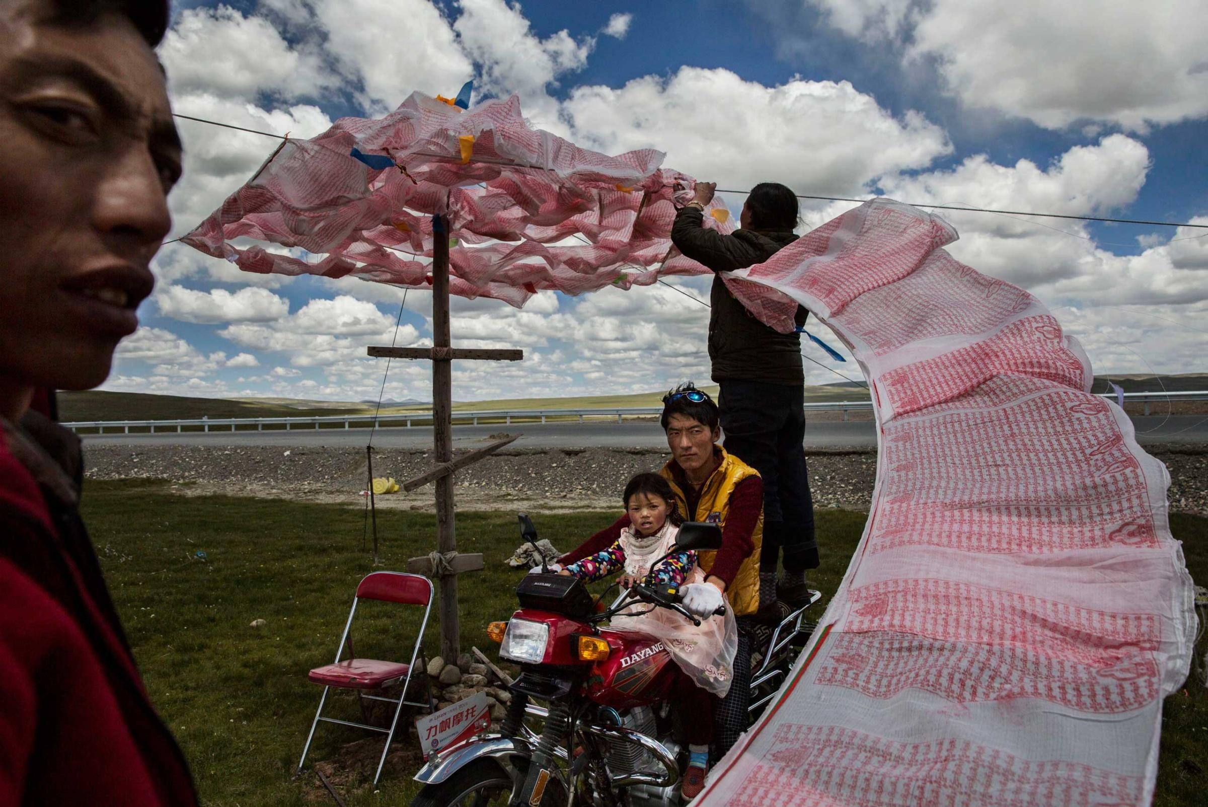 Professional Environment First Place. Nomadic Life Threatened on the Tibetan Plateau. Tibetan nomads put up a string of Buddhist prayer flags near a government resettlement community on July 24, 2015 on the Tibetan Plateau in Madou County, Qinghai, China.