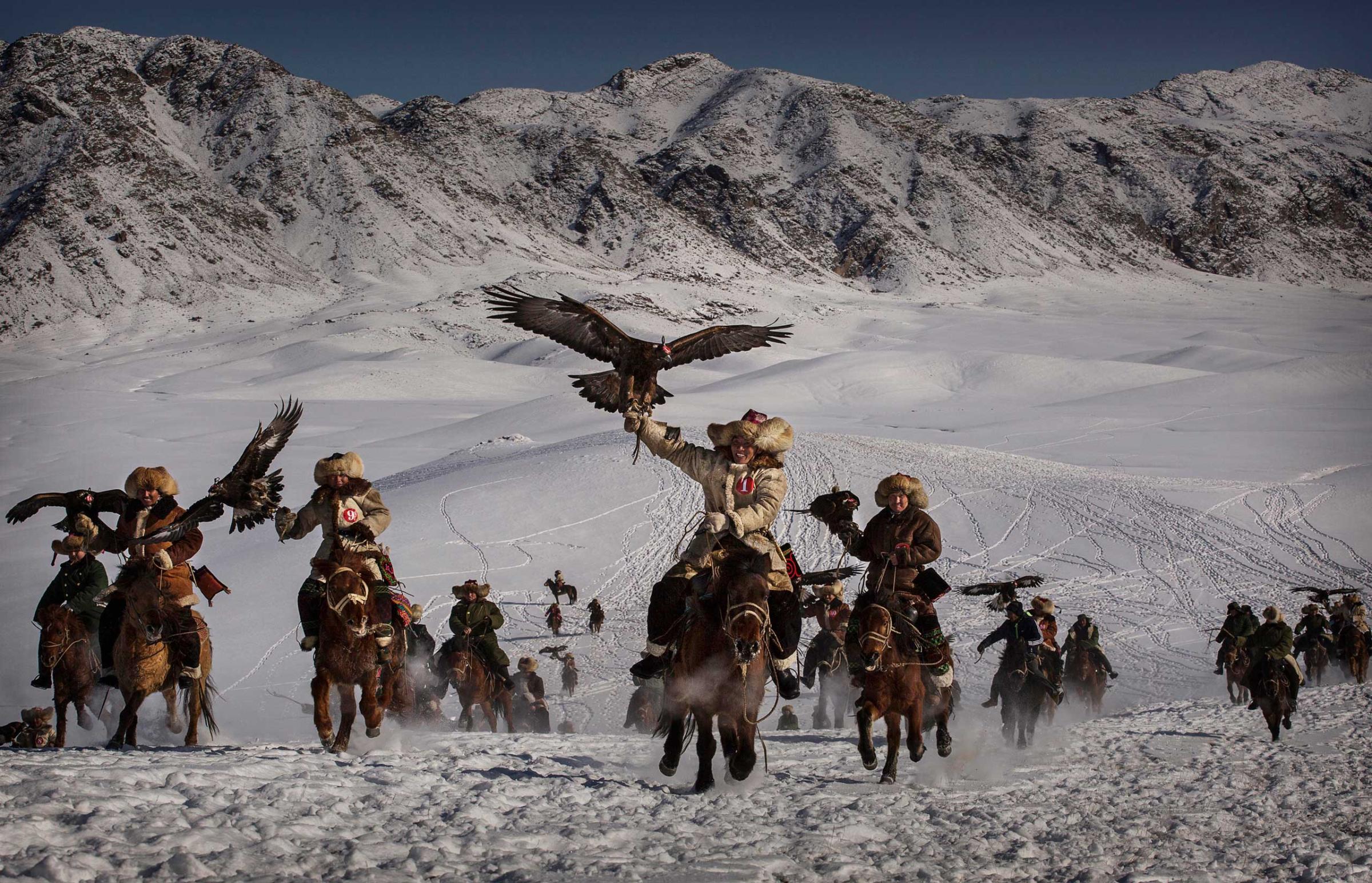Professional People First Place. Eagle Hunters of Western China. Chinese Kazakh eagle hunters ride with their eagles during the competition.